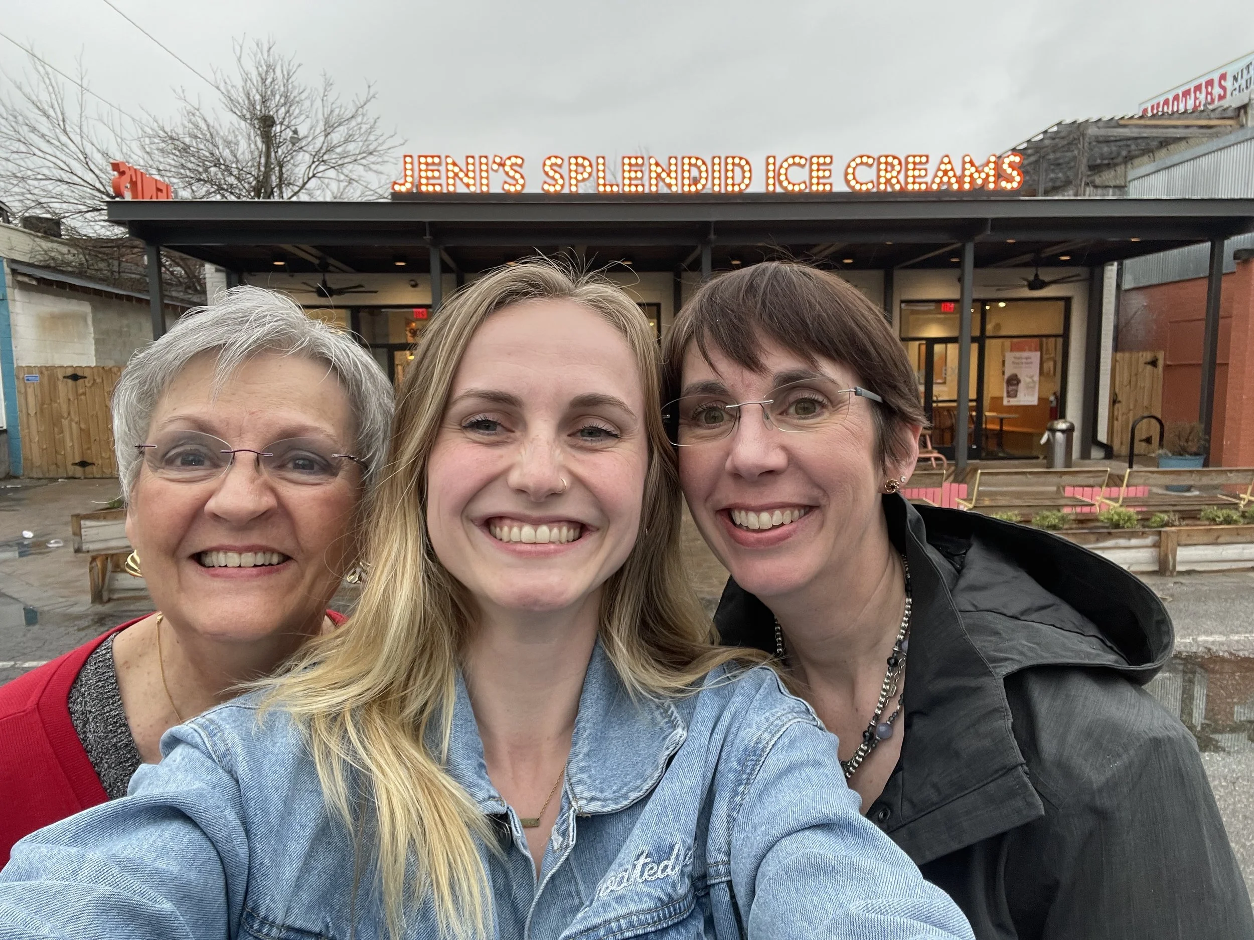 Three women smiling for a selfie in front of Jen's Splendid Ice Creams storefront.