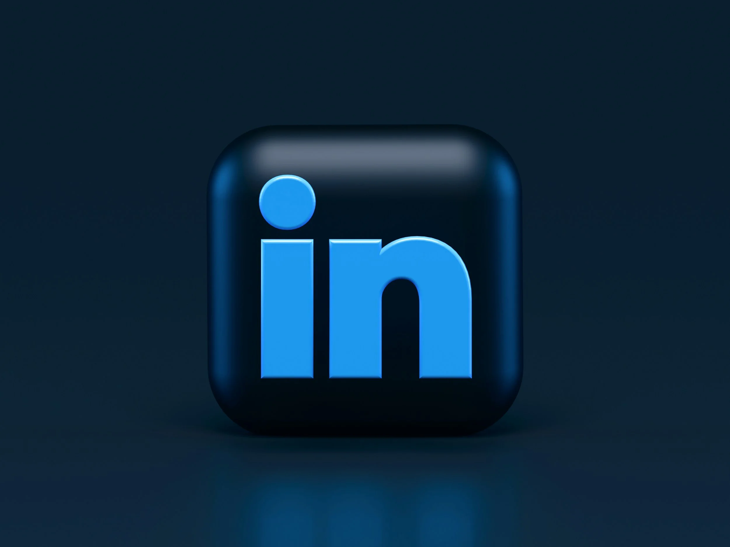 Close-up of a blue LinkedIn logo button with a dark background.