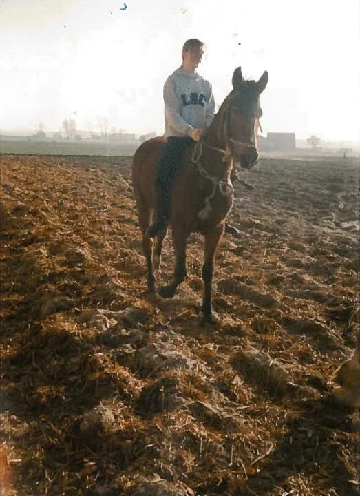 Teen girl riding a horse bareback in a plowed field during sunset.