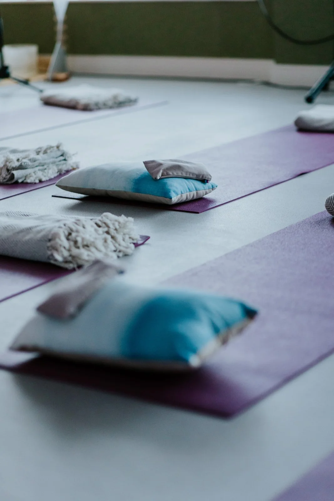 Yoga mats with small pillows and blankets on the floor in a meditation or yoga class.