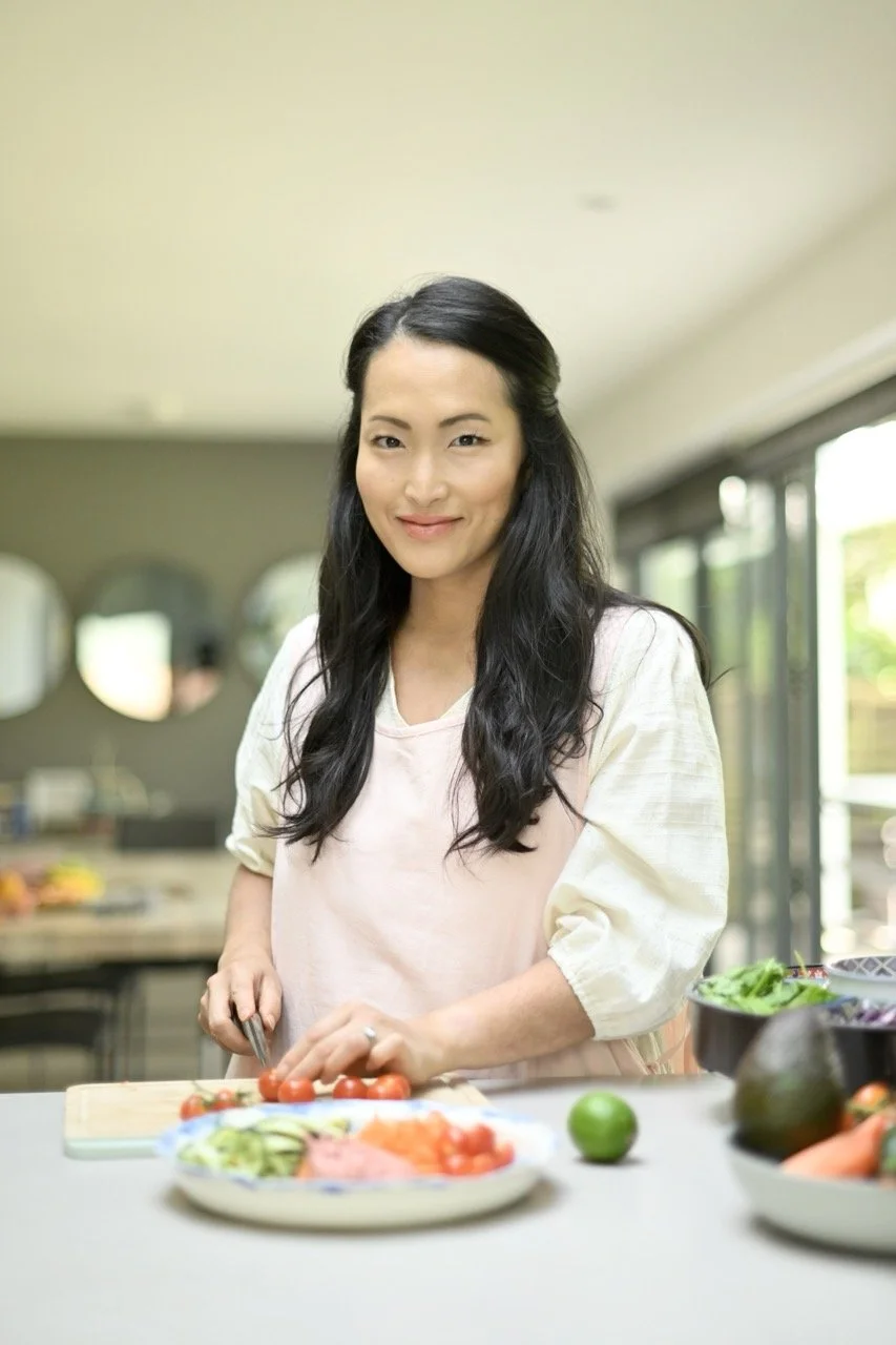 A woman with long black hair preparing cherry tomatoes in a kitchen.