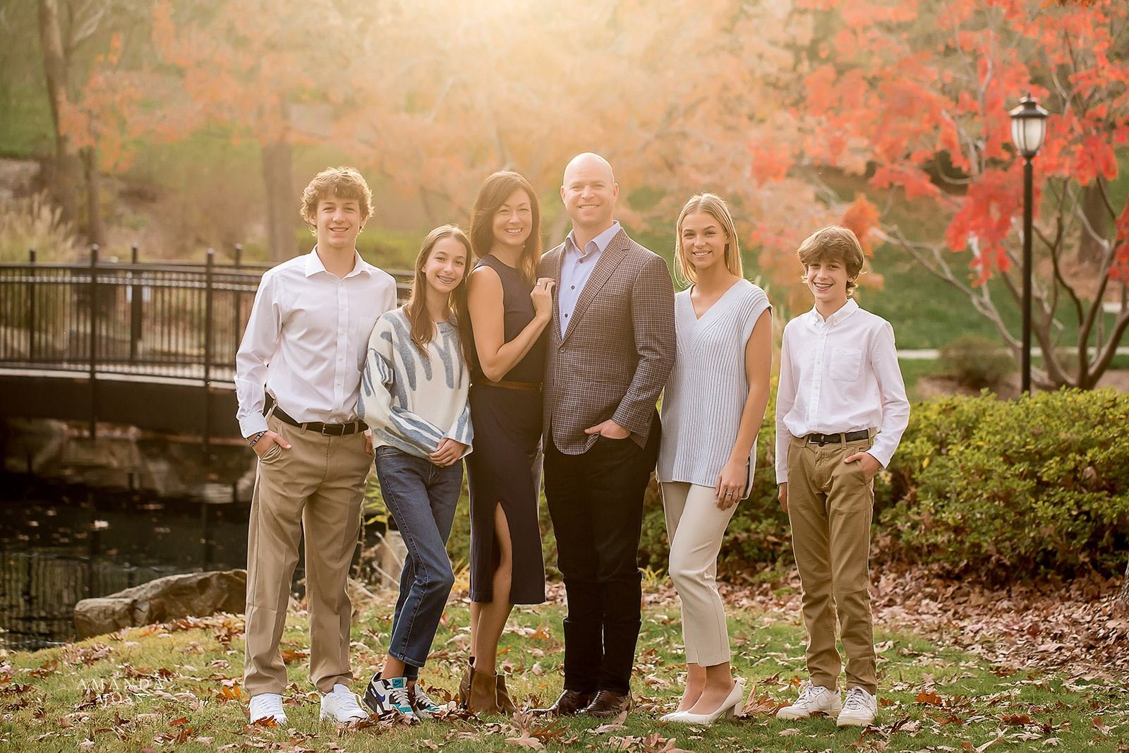 fall family photo with mom and dad, two sisters and two brothers standing in front of fall foliage