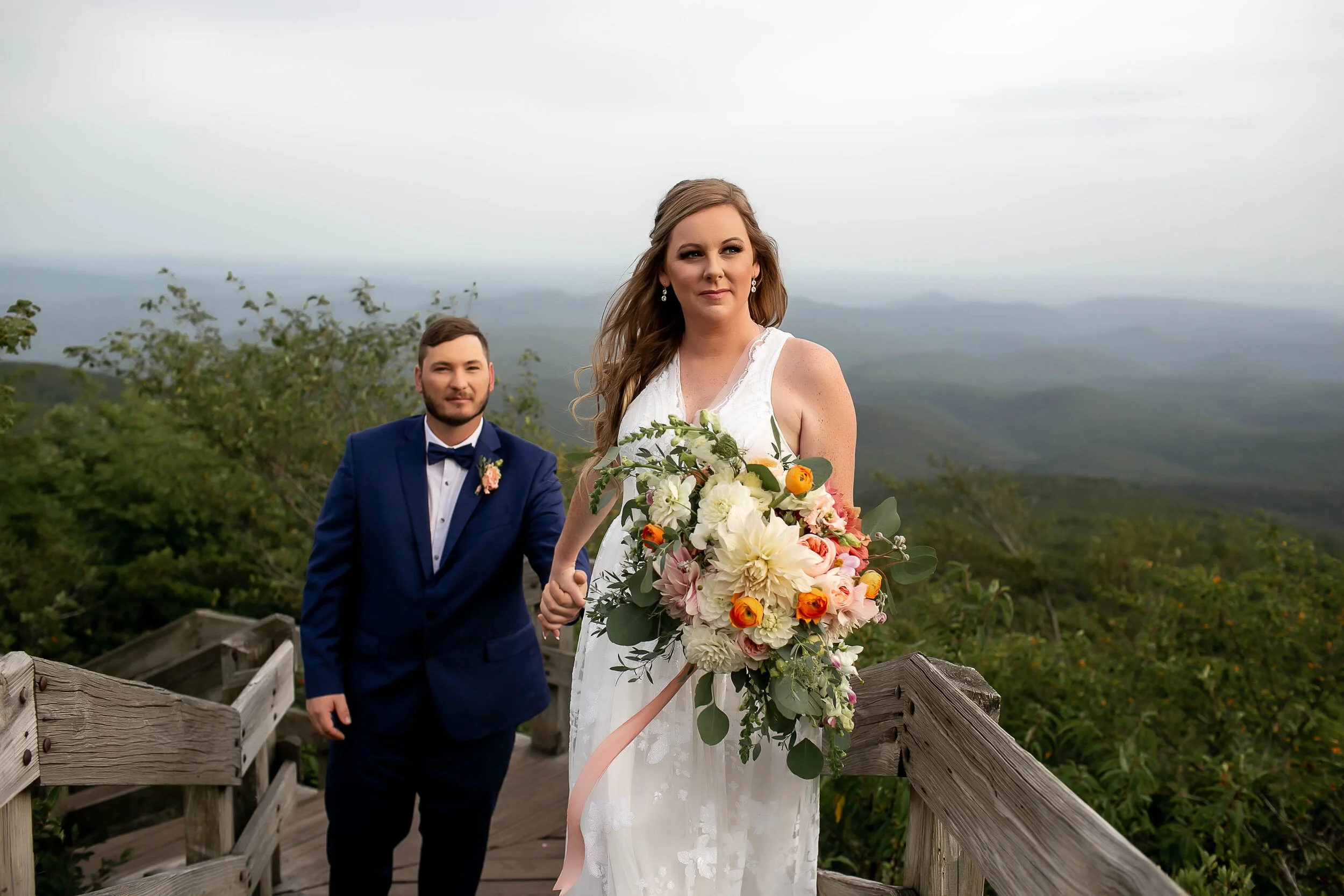 Bride leads groom up wooden stairs at blueridge parkway rough ridge overlook
