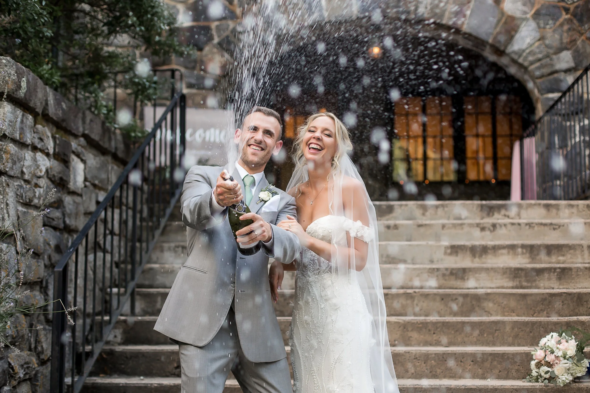 Bride and groom spray champagne in celebration of their wedding