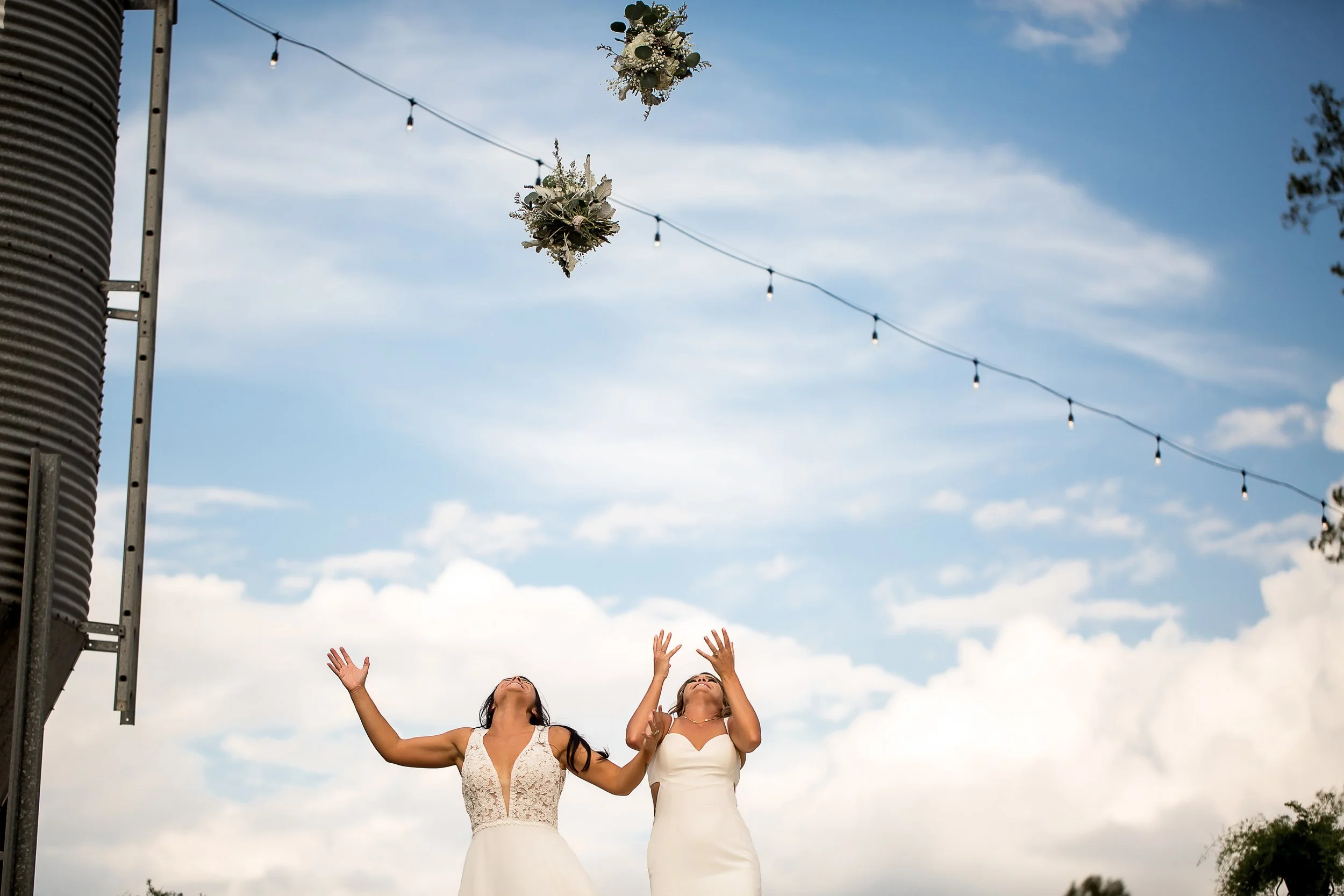 two brides lgbt wedding throw their bouquets in the air in celebration