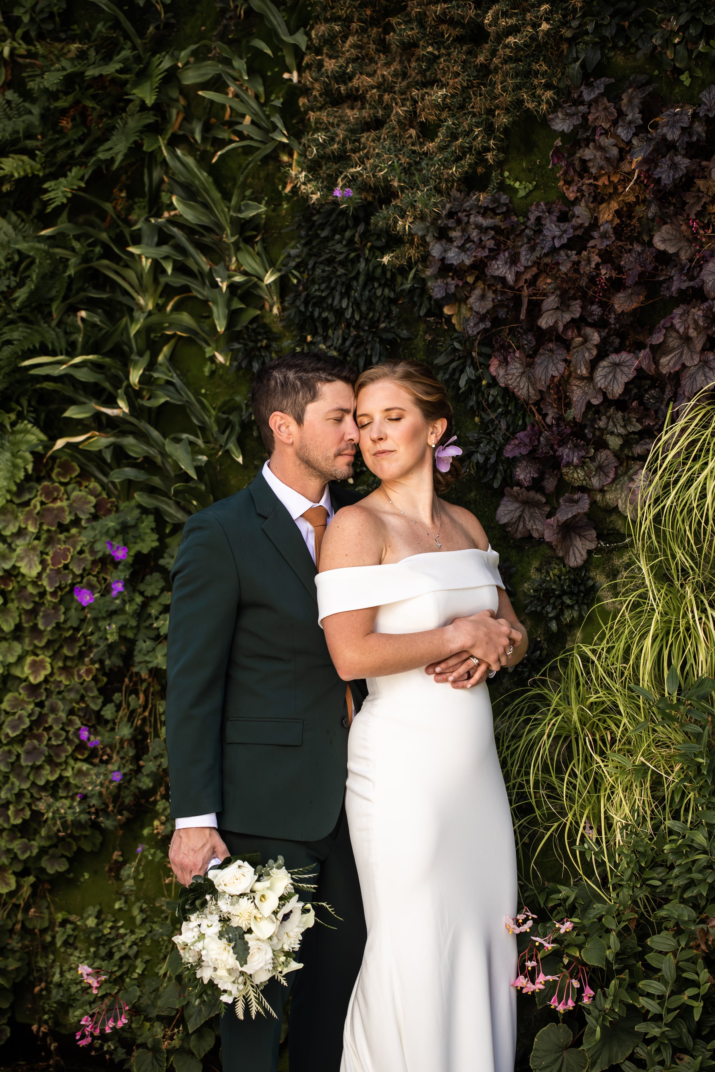 fftc foundation for the carolinas intimate rooftop wedding bride and groom embrace with eyes closed in front of greenery wall