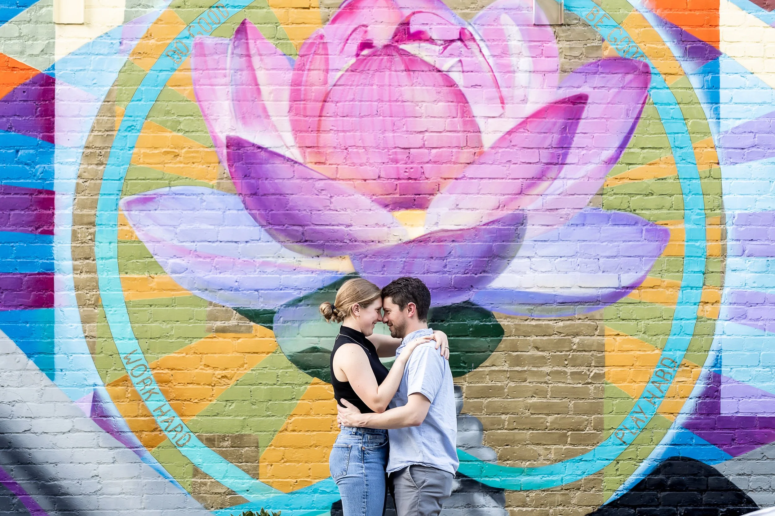 young couple embraces in front of colorful lotus mural in noda charlotte nc
