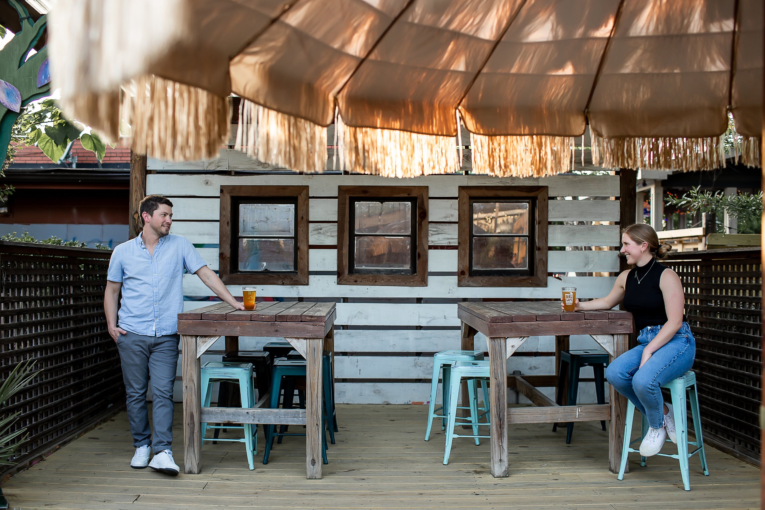 smiling engaged couple sharing beer in tiki style outdoor patio bar charlotte nc