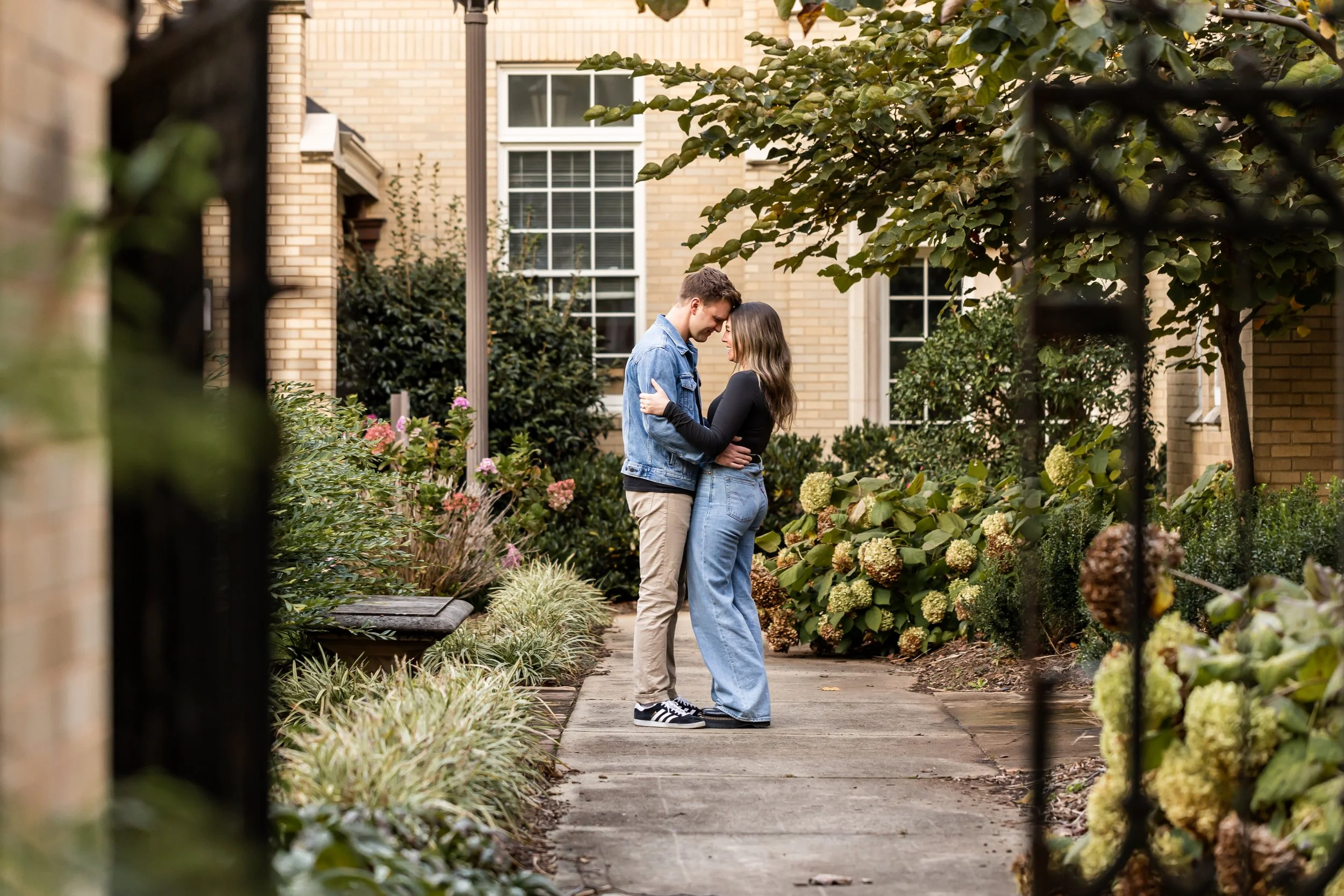 couple in jeans rests their foreheads together in courtyard charlotte nc church surprise proposal photography