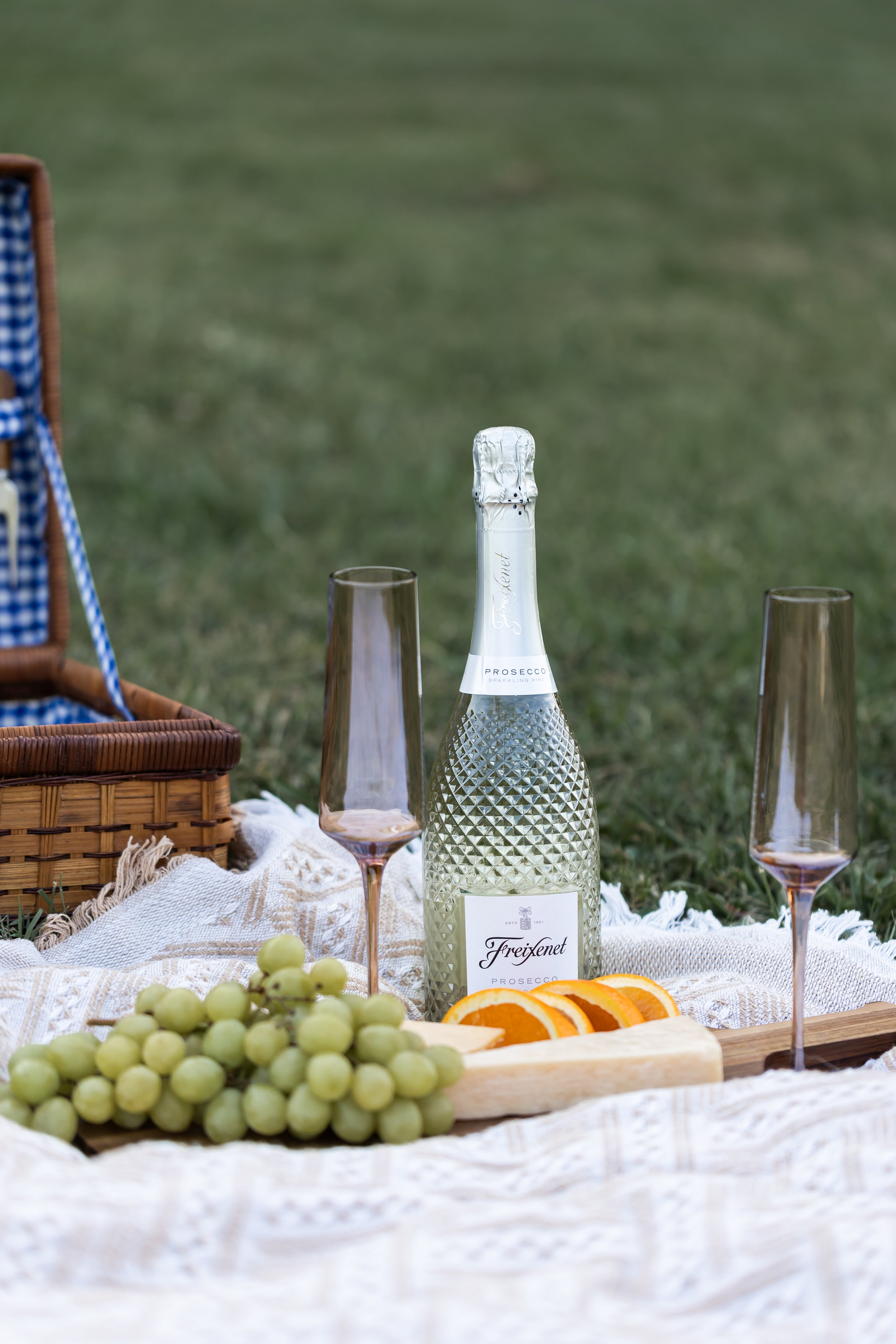 detail photo of picnic engagement session set up with wine grapes orange cutting board and picnic basket