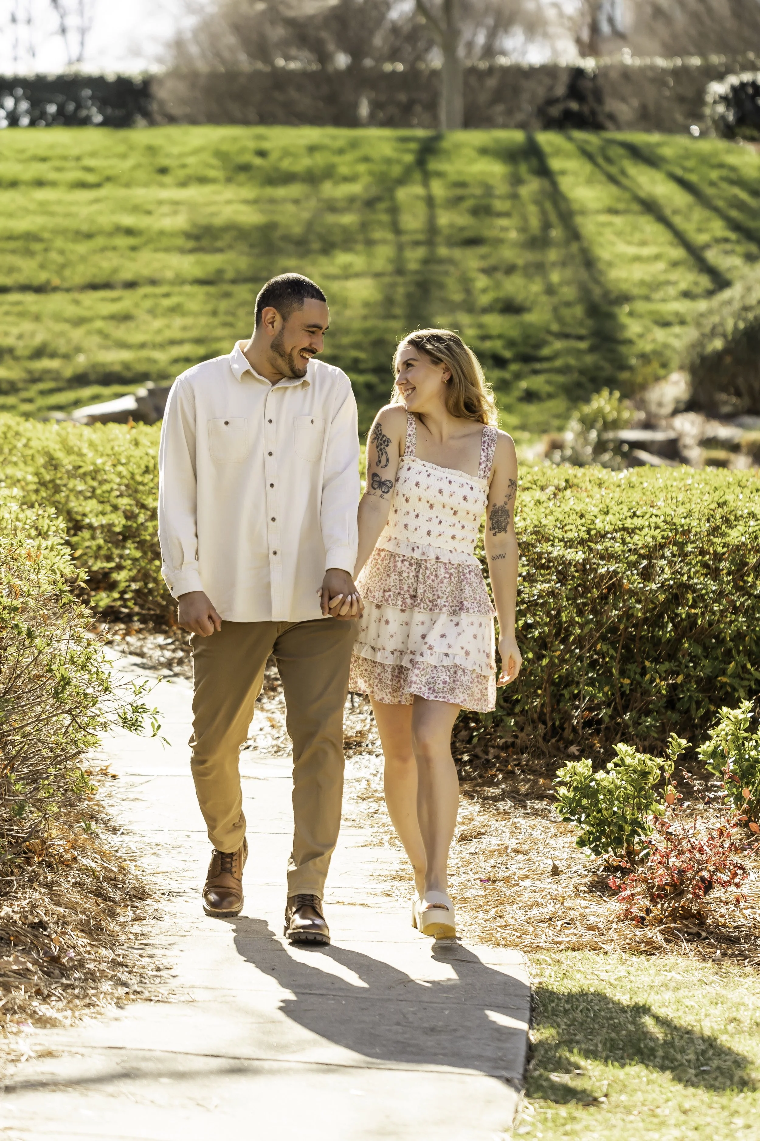Engagement portraits of Erick and Faith near the lake at Cullman Park, with lush greenery in the background