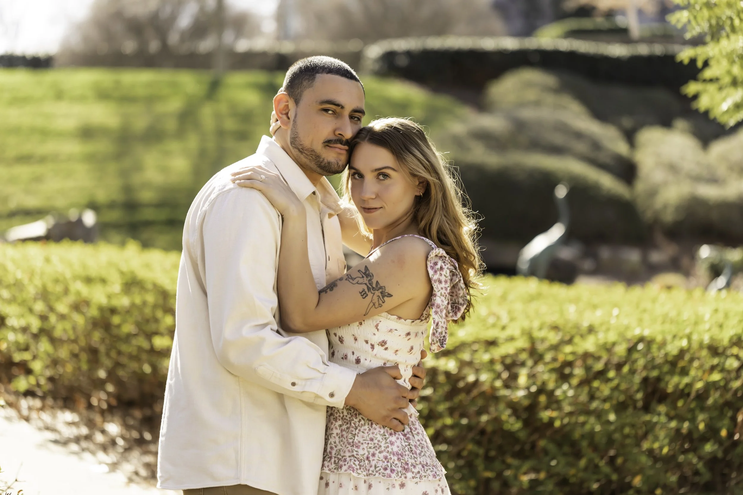 Engagement portraits of Erick and Faith near the lake at Cullman Park, with lush greenery in the background