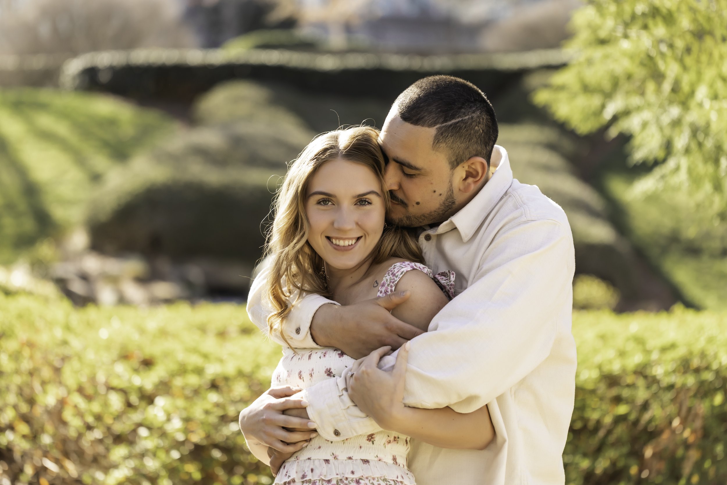 Engagement portraits of Erick and Faith near the lake at Cullman Park, with lush greenery in the background