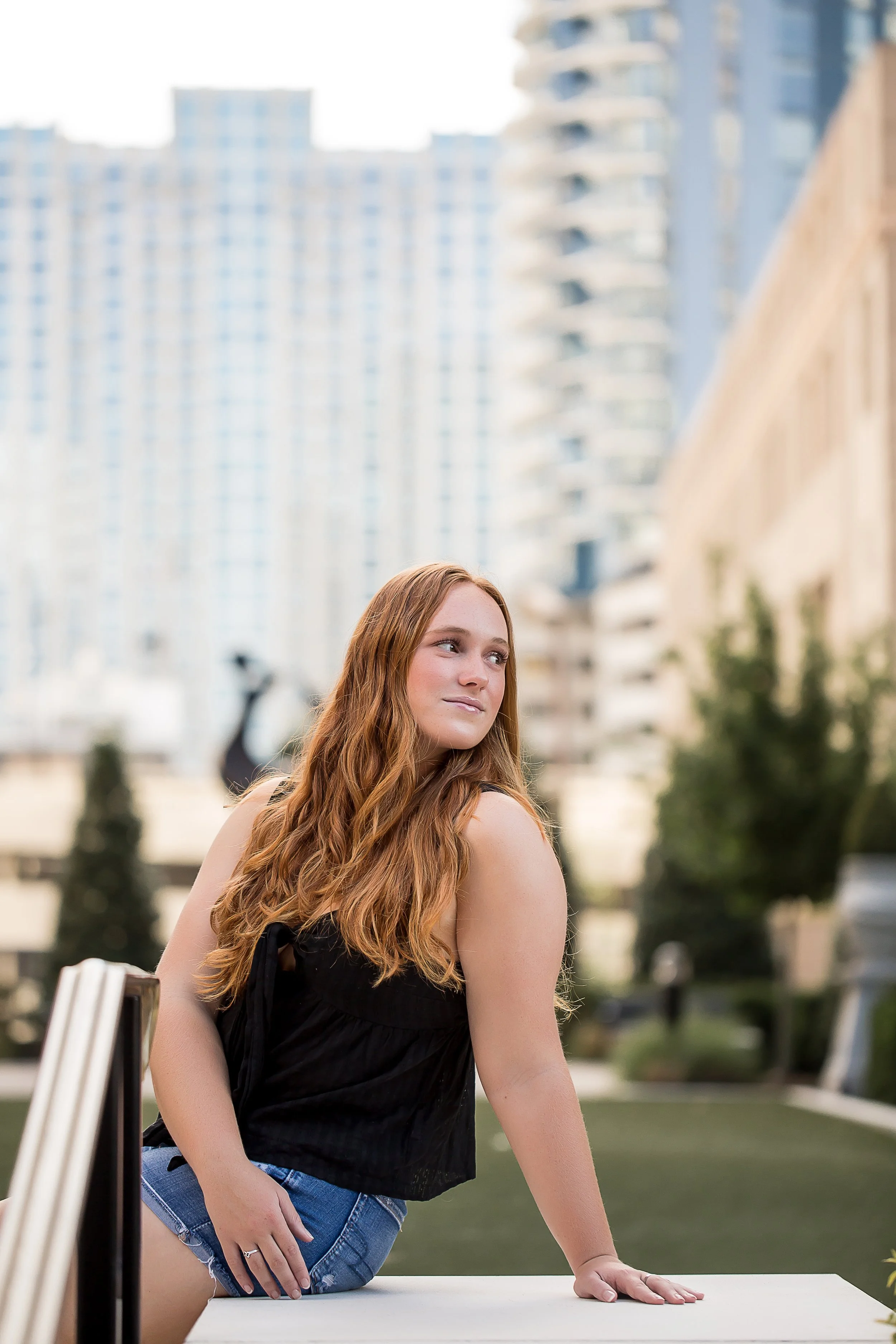 red head high school senior poses for photo in front of city buildings charlotte senior photographer