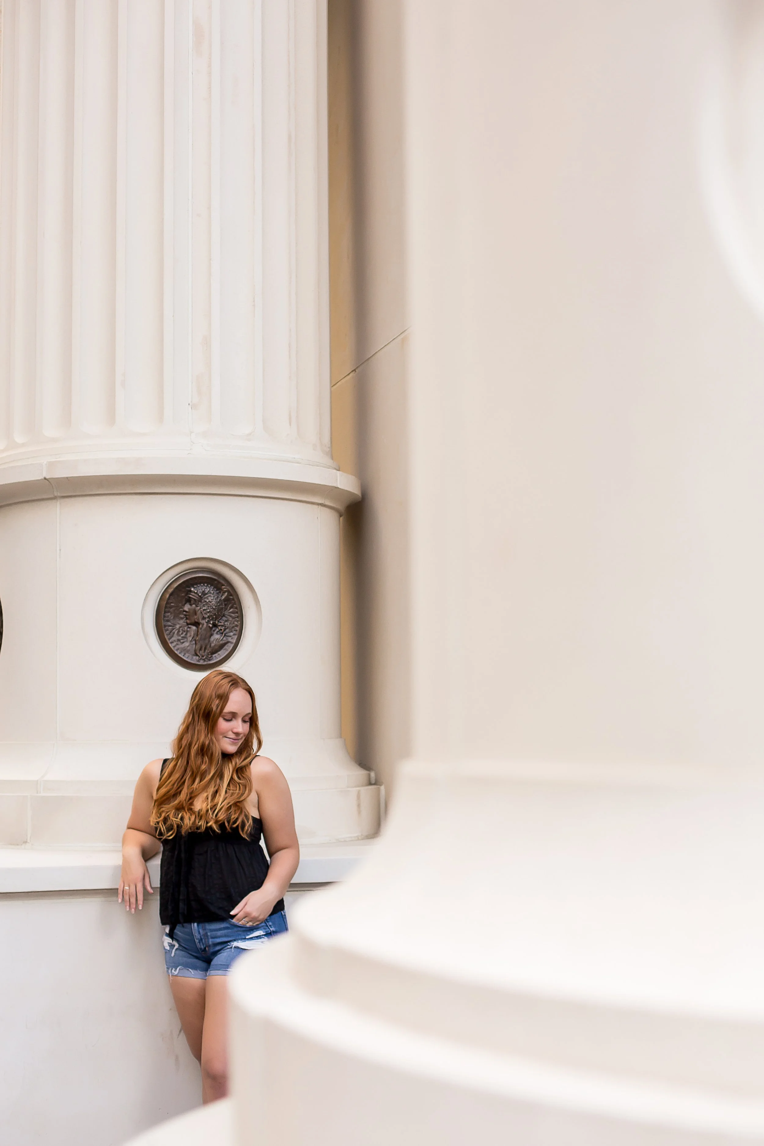 senior photo redhead girl poses among tall city columns