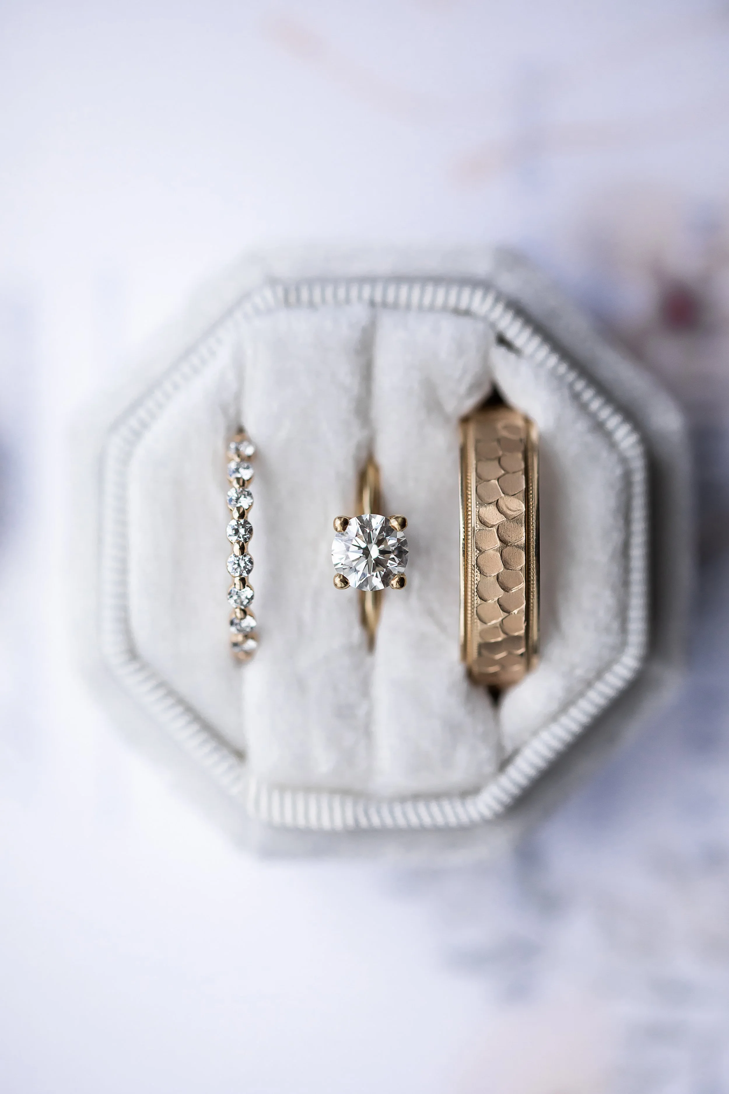 Elegant ring shot of wedding bands and engagement ring placed on a marble surface for a clean, modern look