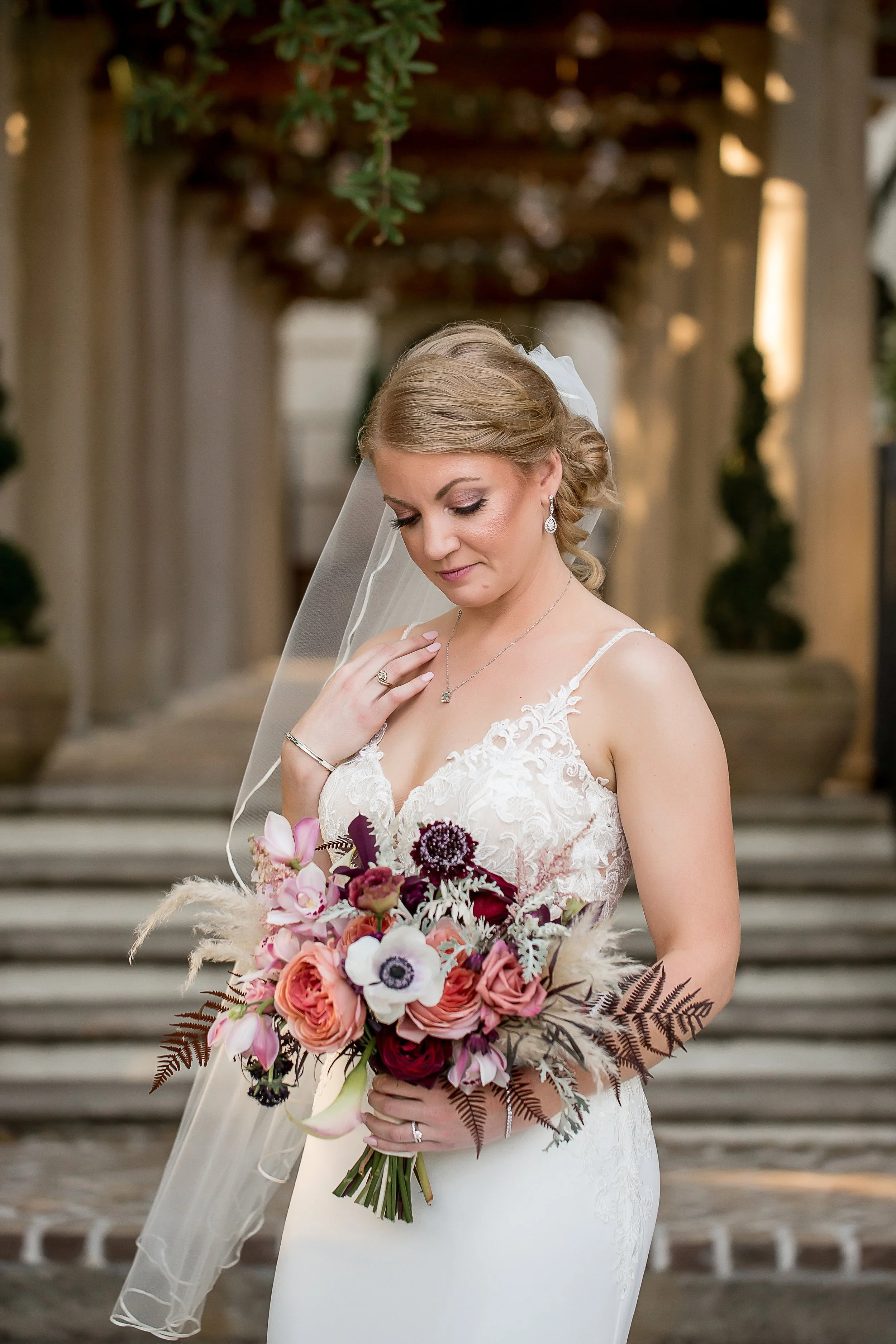 beautiful bride looks down at her delicate flower in front of charleston low country mansion