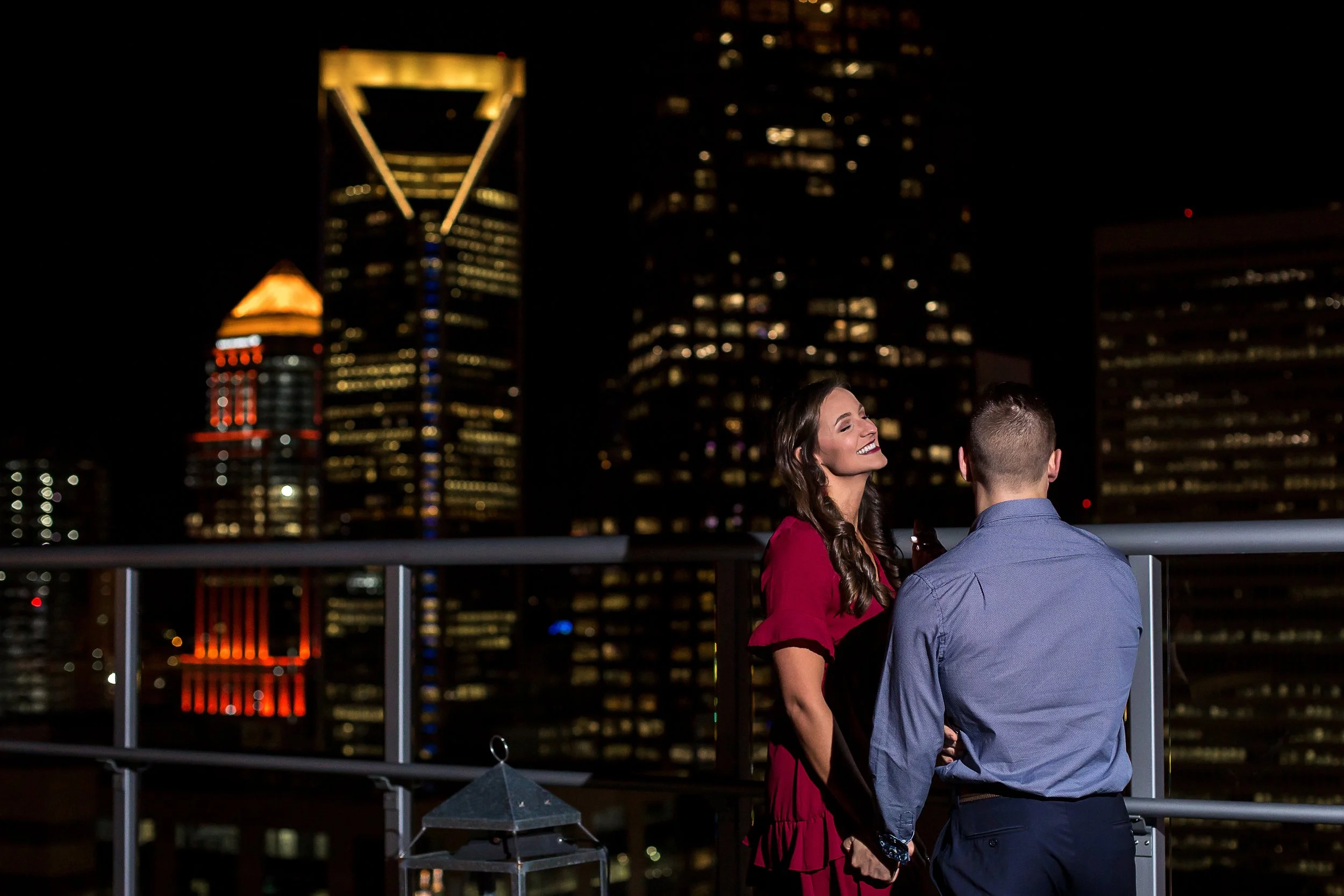 couple on charlotte uptown rooftop skyline in background night
