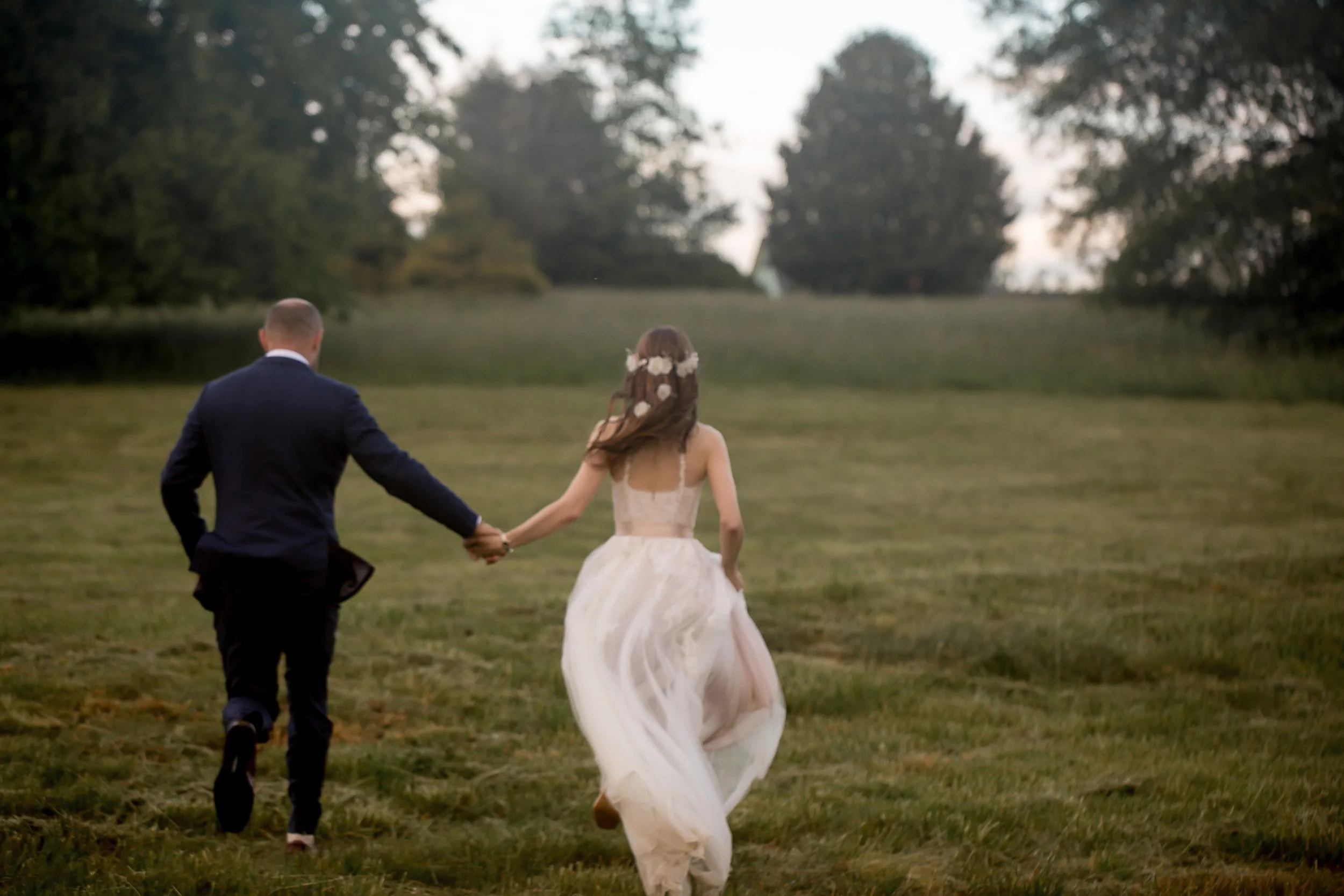 candid documentary style wedding photo of a couple running through a rainy field daniel stowe botanical garden