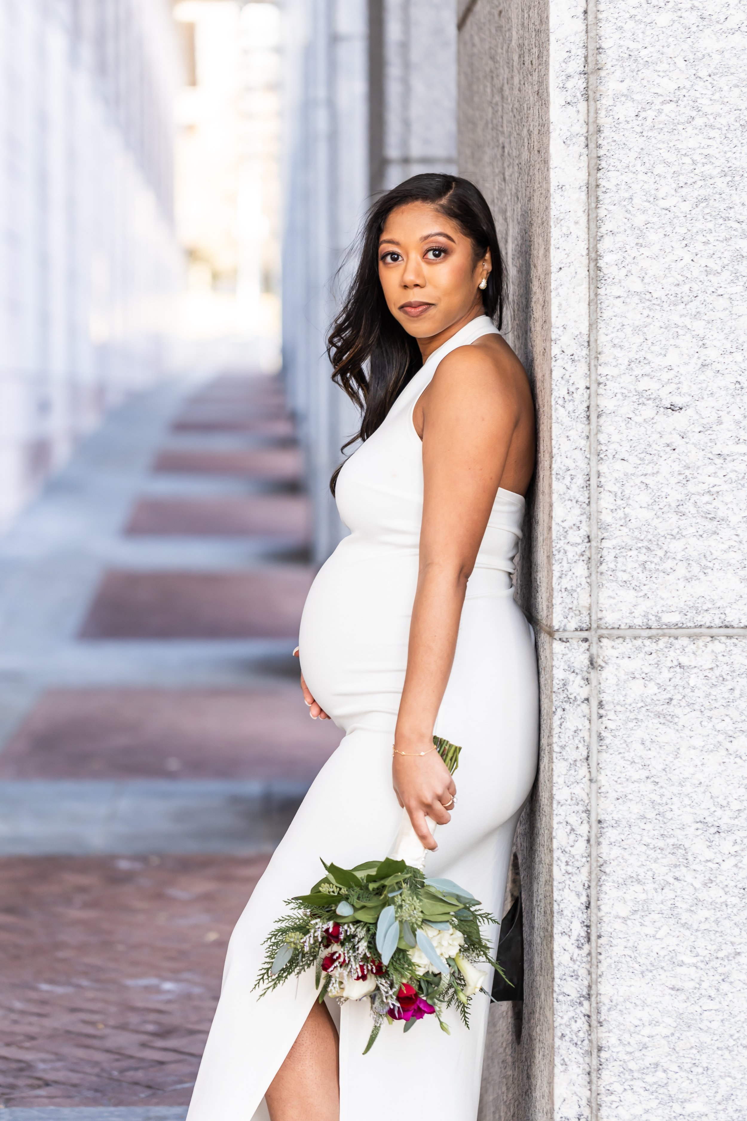 beautiful pregnant bride in sleek white dress holding flower bouquet downtown charlotte nc elopement photographer