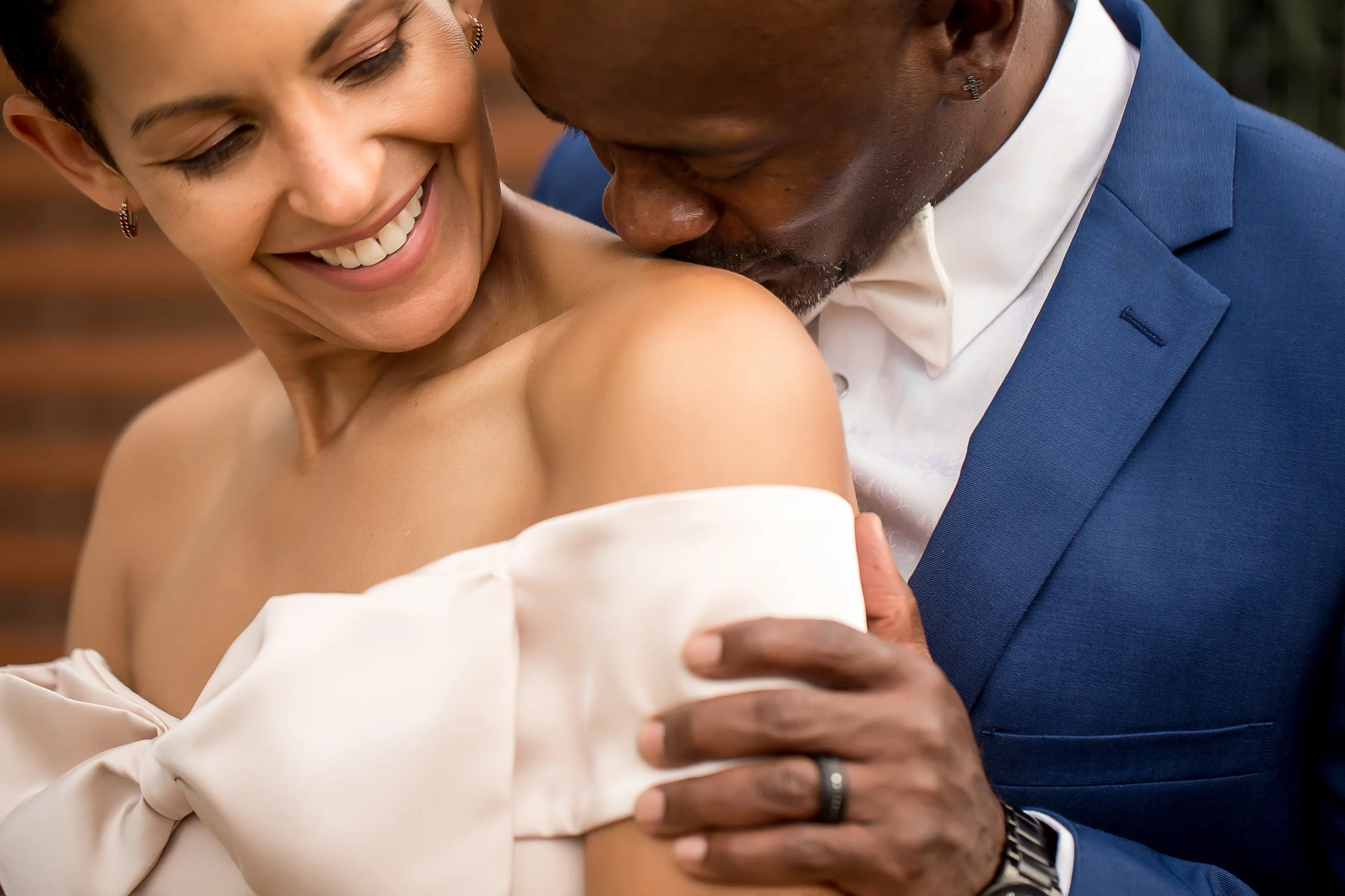 black couple kissing shoulder after elopement navy suit satin bow dress