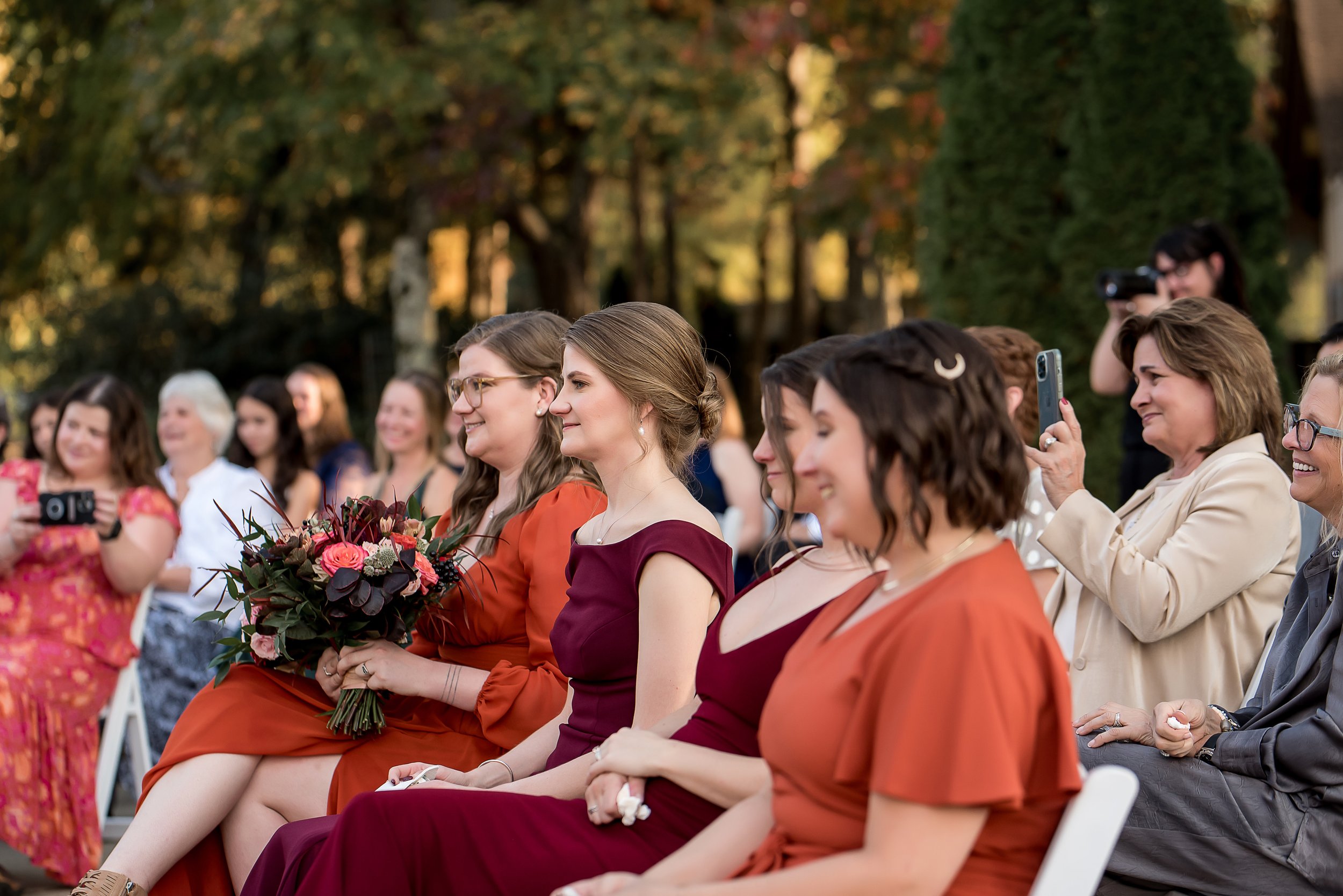 small micro wedding of 30 guests witness a couple get married. Fall colored bridesmaids dresses.