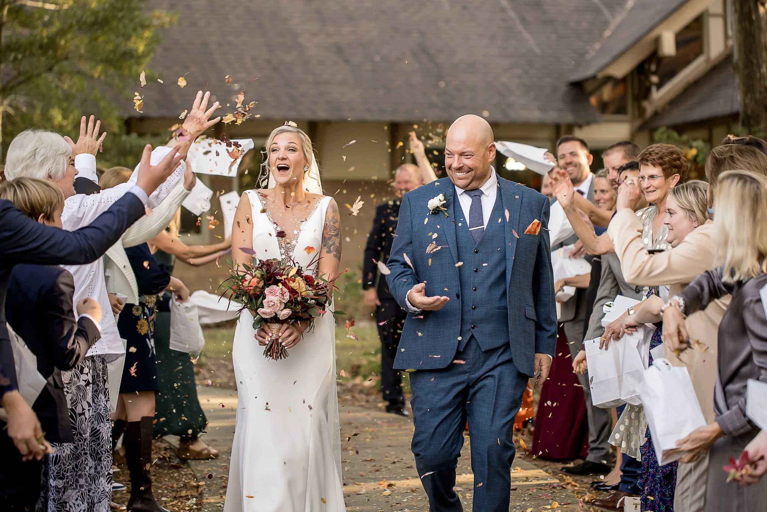 wedding photo of a couple walking through their guests throwing dried flowers microwedding fall outdoors matthews nc