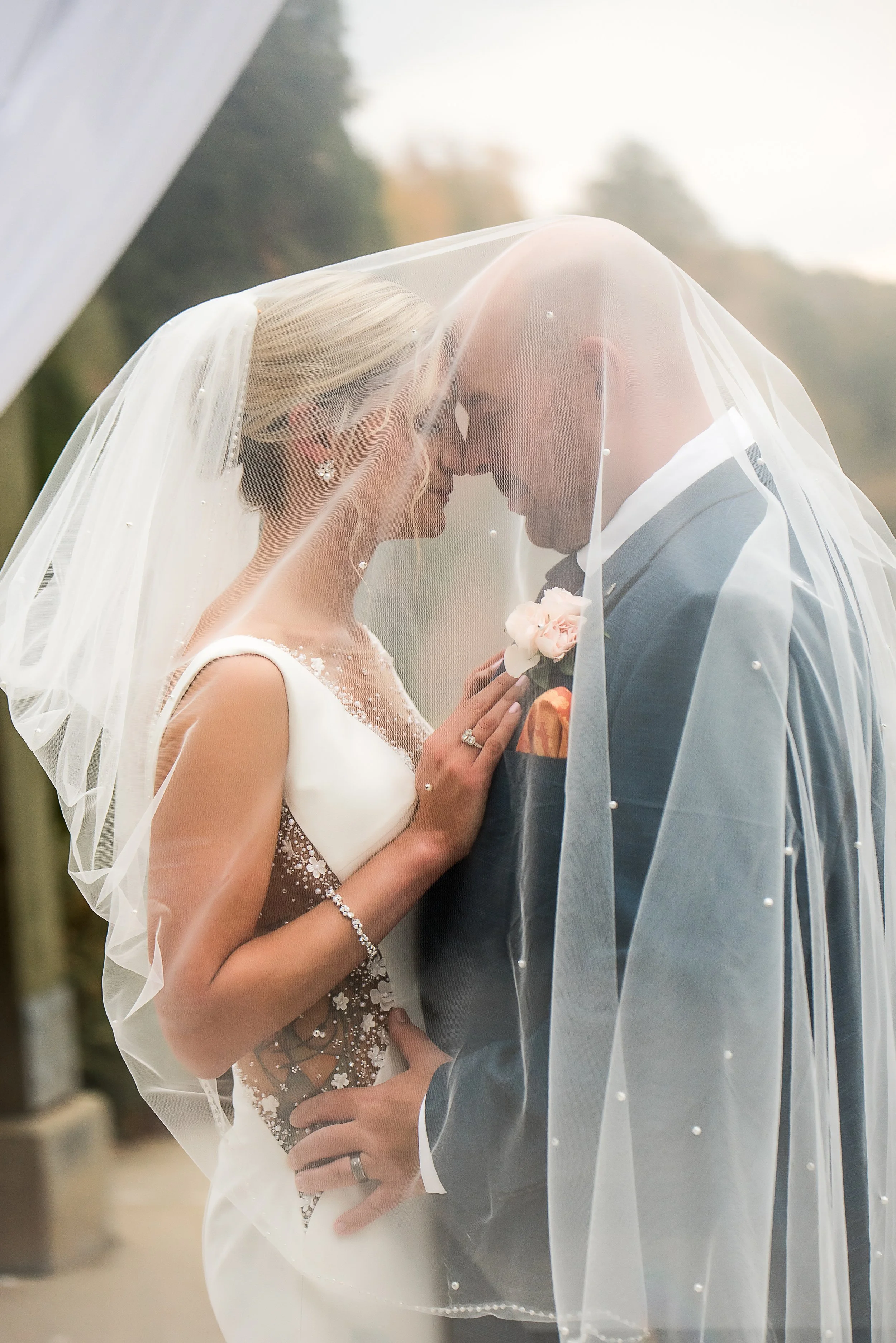 intimate wedding photo bride and groom embrace under veil in overcast light matthews nc charlotte north carolina