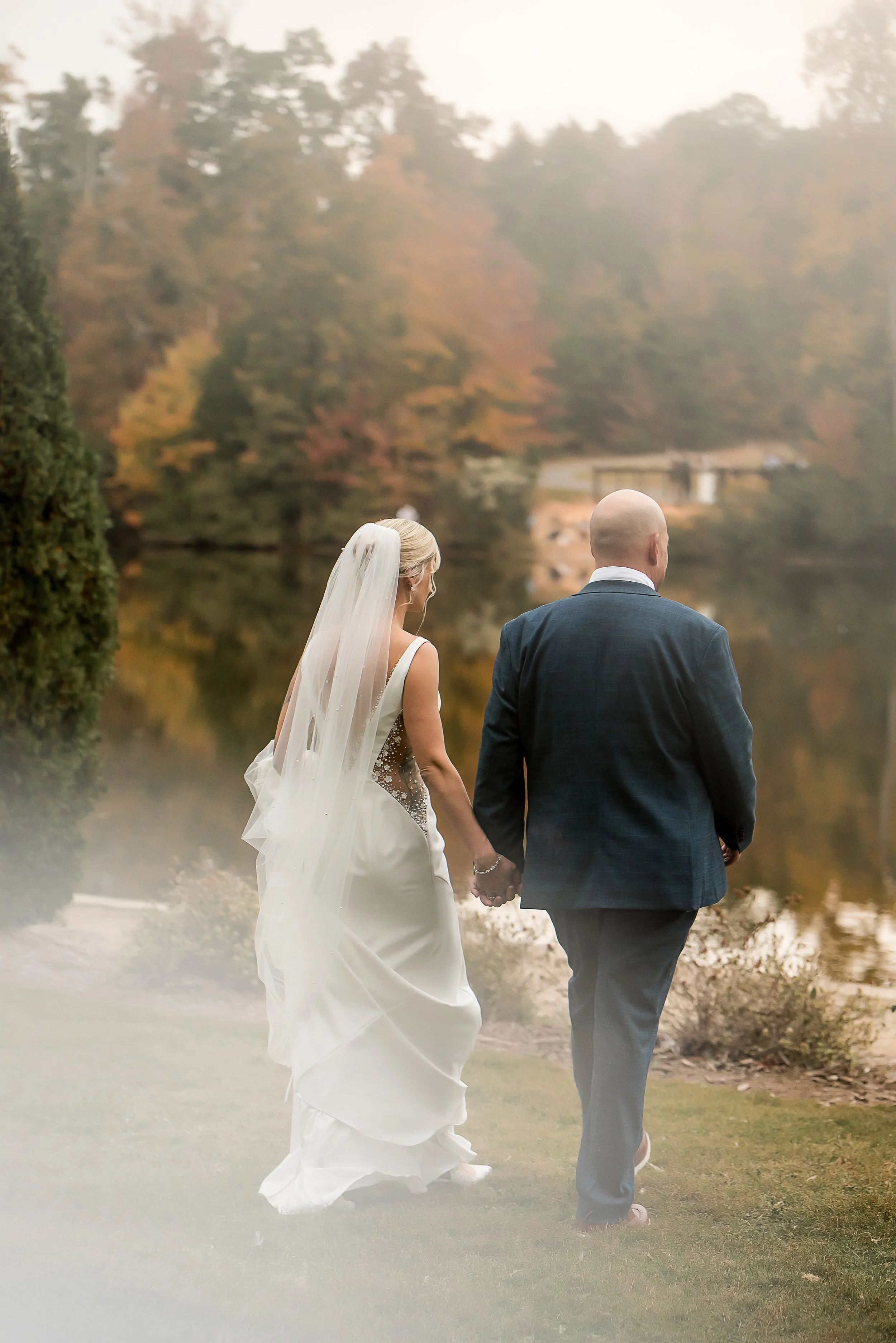 fall wedding couple walks to lake matthews north carolina