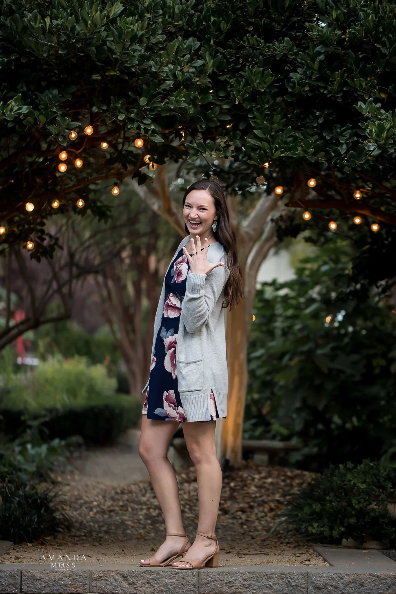 photo of young woman in floral dress showing off new engagement ring