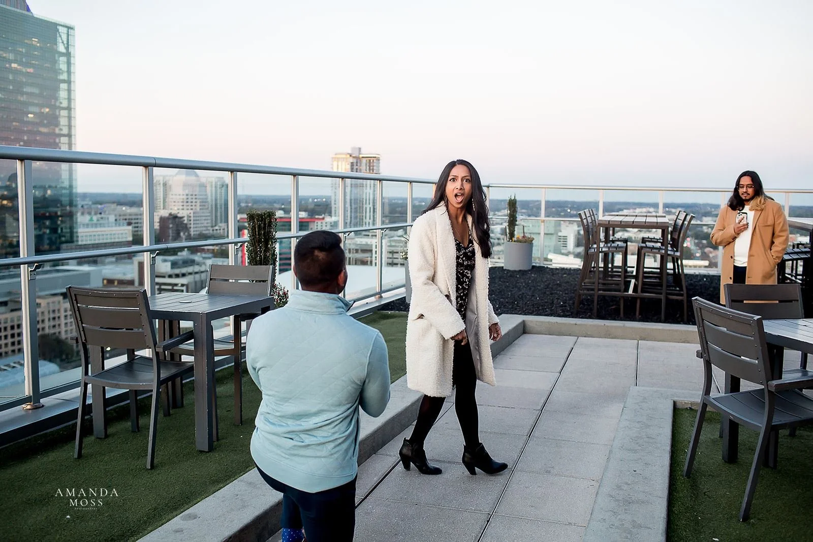 woman is stunned to turn around and find her boyfriend on one knee proposing to her on fahrenheit rooftop patio