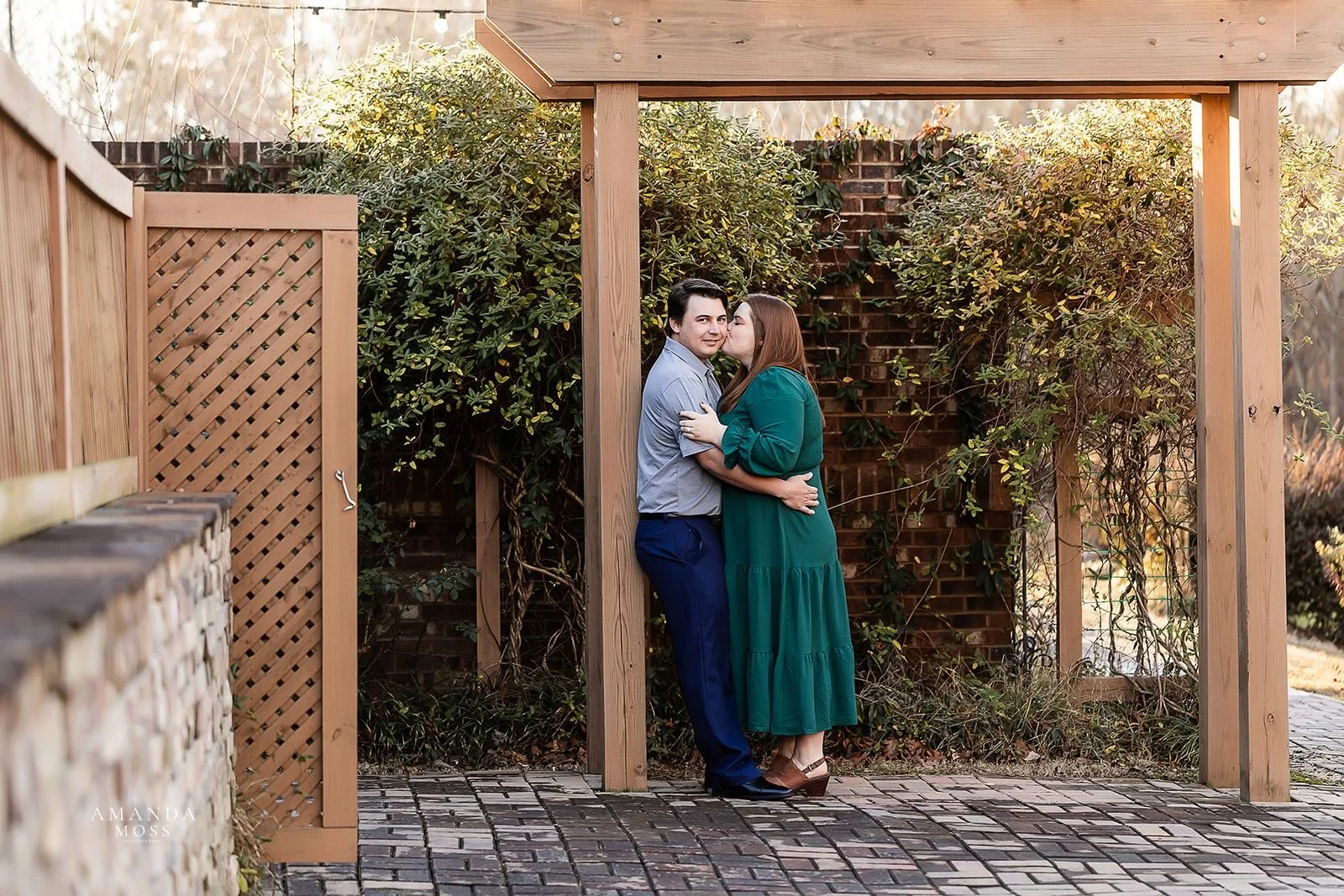 woman kisses her fiance on the cheek at magnolia woods in huntersville nc for engagement session