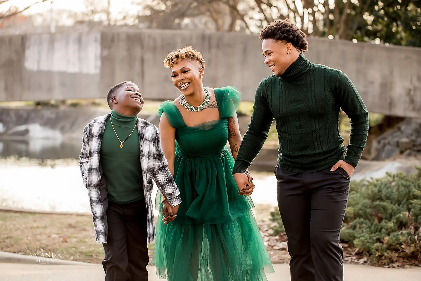 mother and two sons hold hands and smile at family session at marshall park in charlotte nc