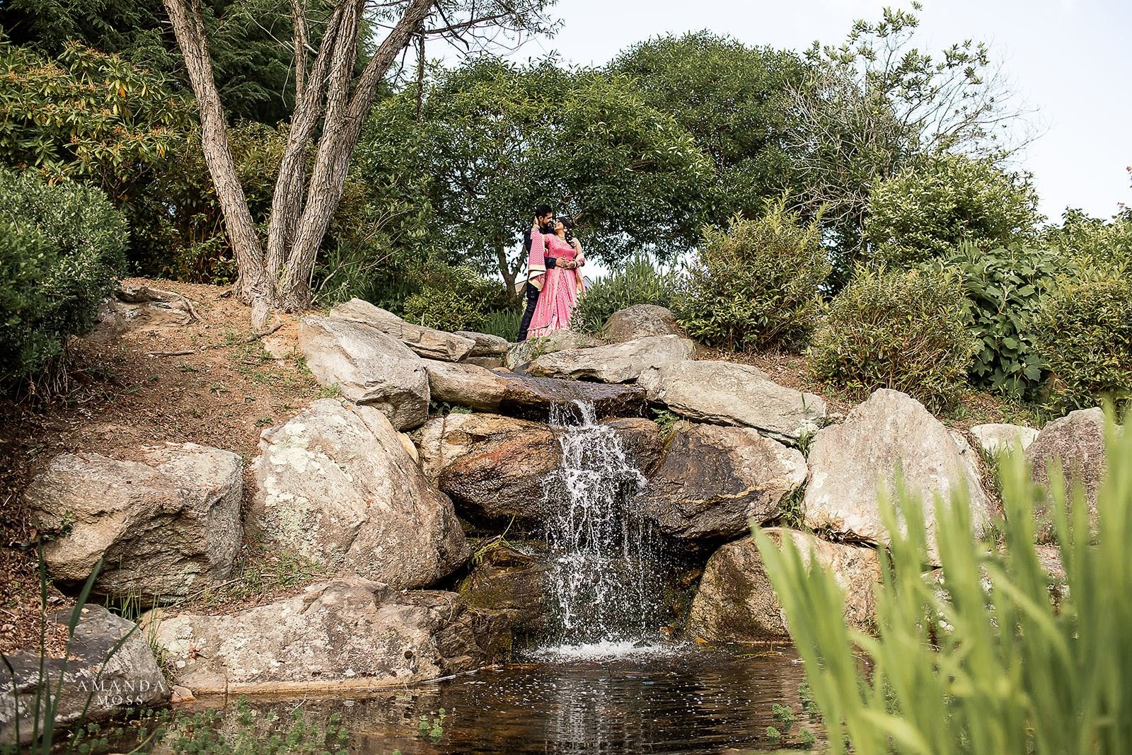 Hindu bride and groom pose above waterfall at sangeet ceremony in Ashville
