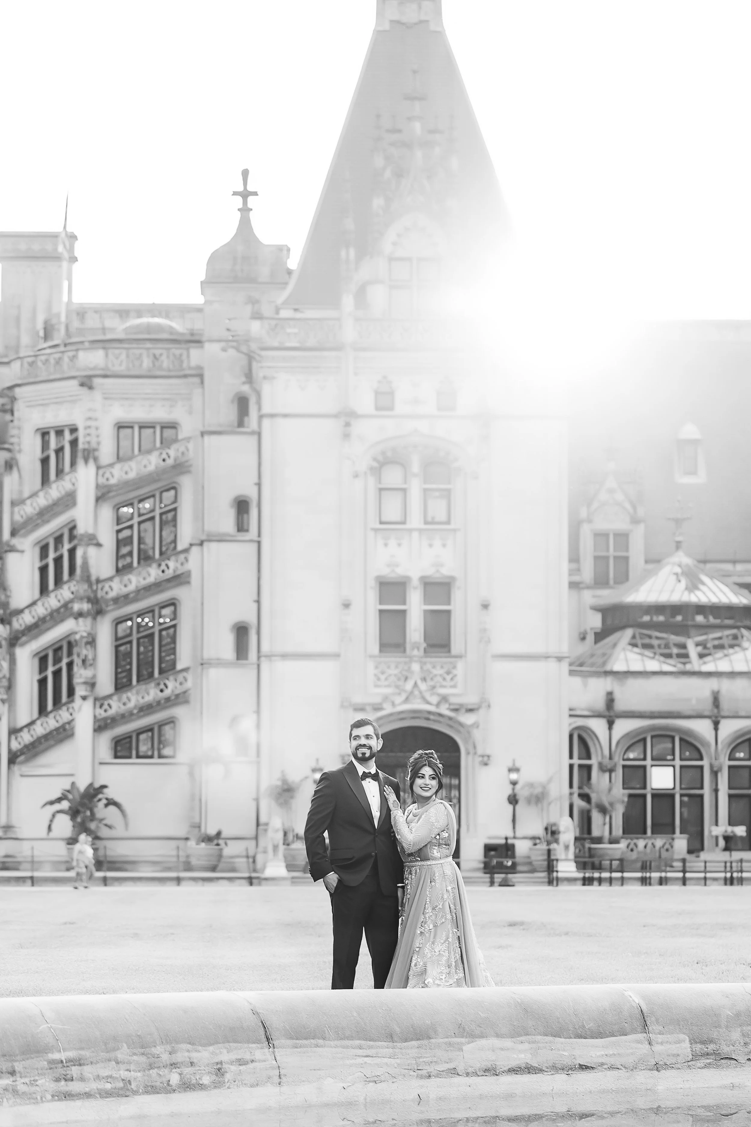 indian bride and groom embrace in front of the biltmore estate in a classic black and white photo