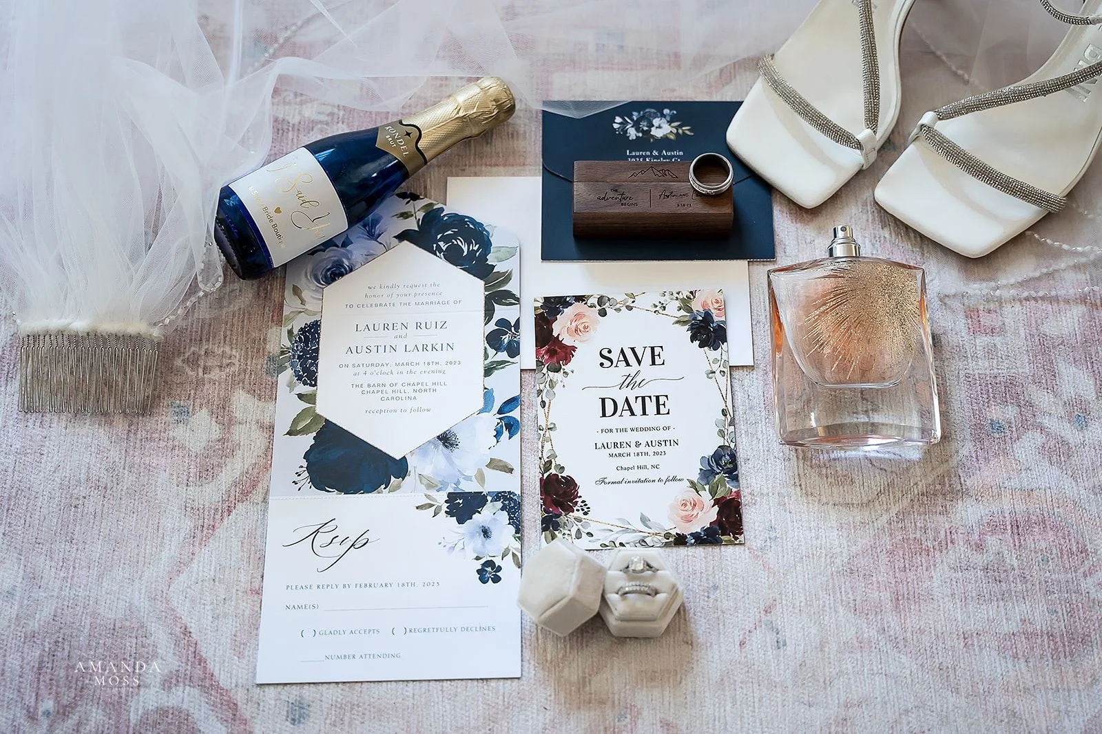 flat lay of wedding detail including shoes champagne perfume rings and invitation suite