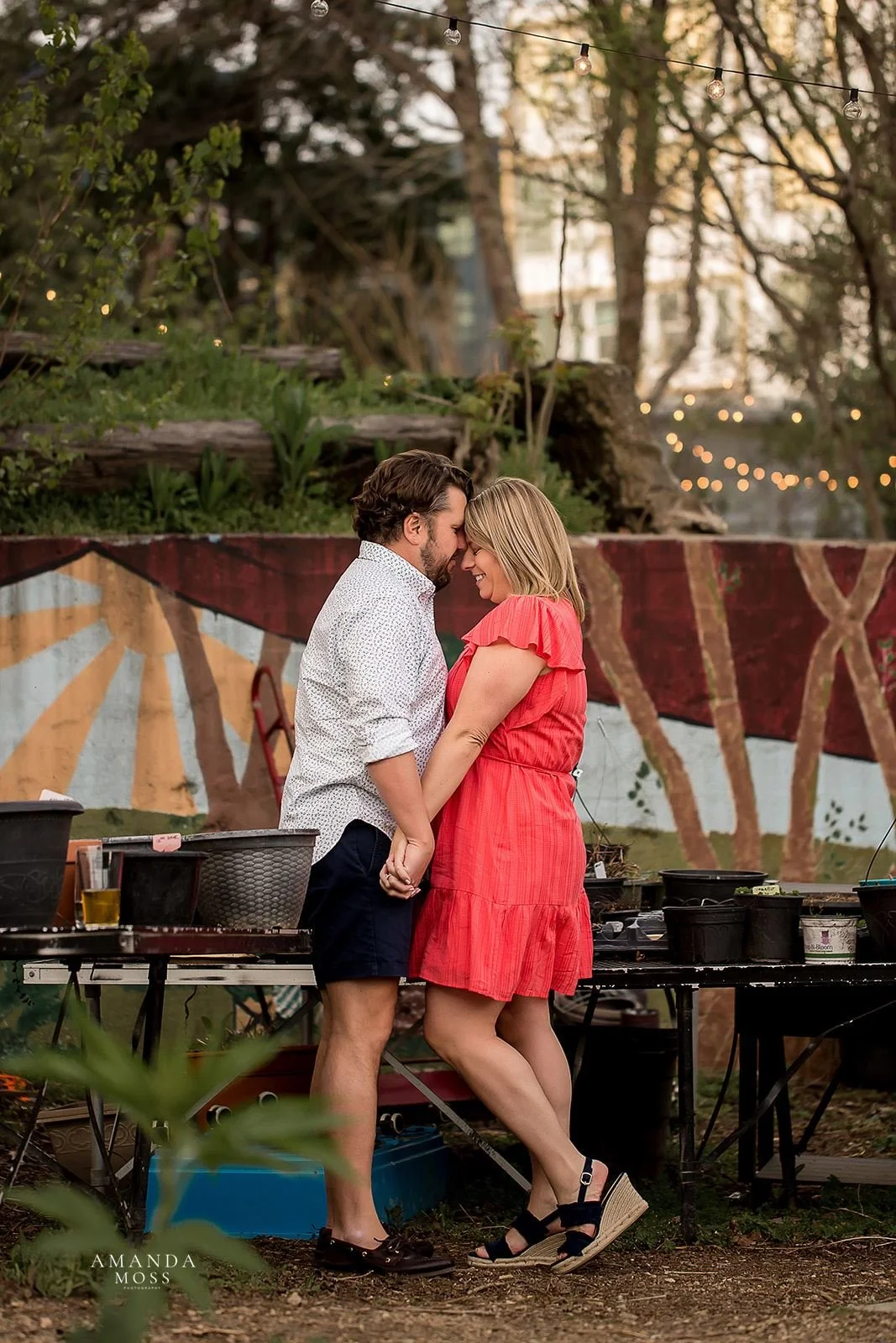 couple holds hands and embraces with foreheads touching at rosies wine bar during engagement session in charlotte nc