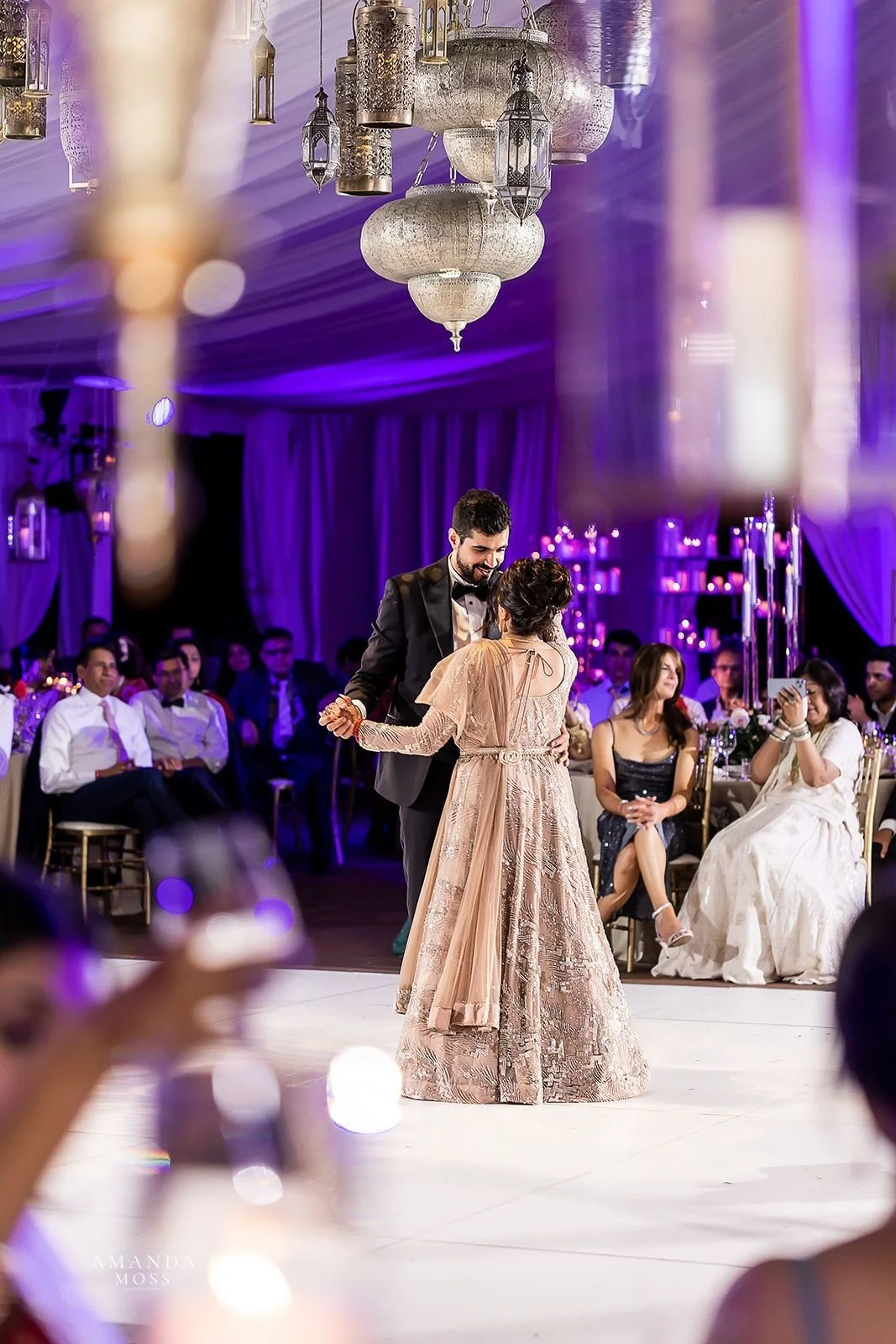 Hindu bride and groom share first dance under purple and gold lighting at wedding reception