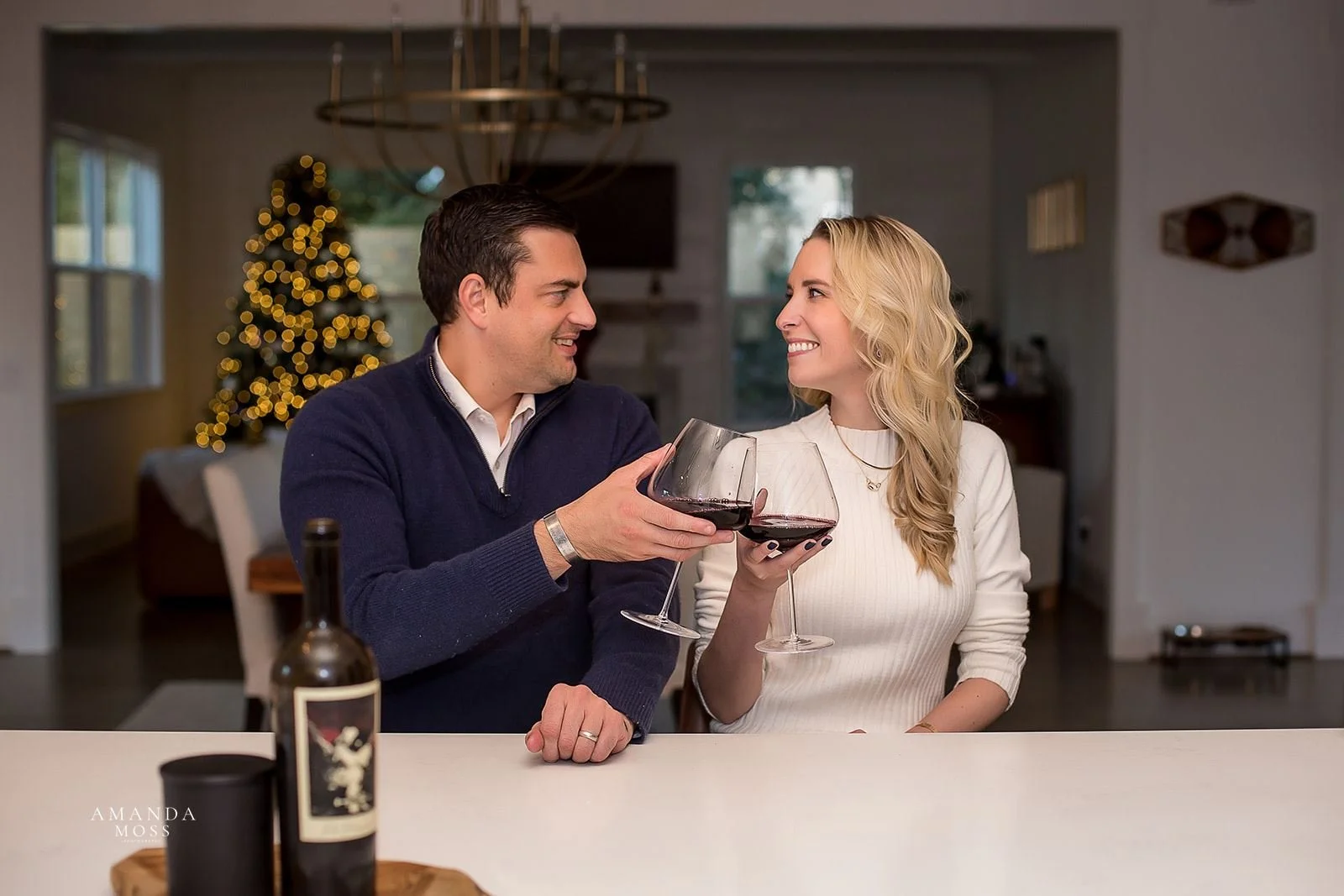 couple clinks wine glasses at bar in new home