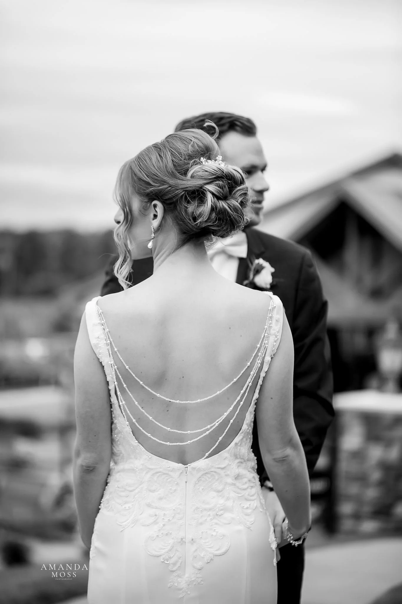 black and white photo of the back of a brides dress with pearls draped across her back