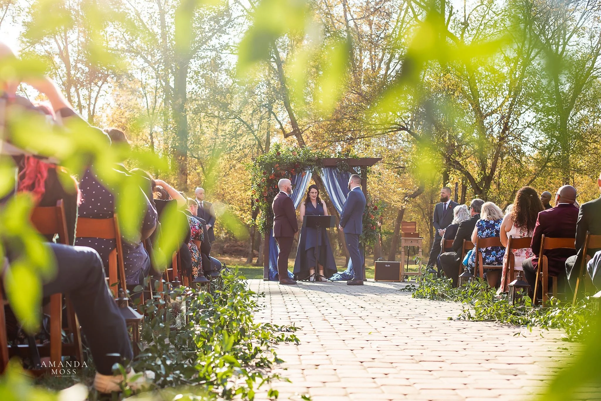 two groom exchange vows during outdoor fall wedding ceremony at providence cotton mill