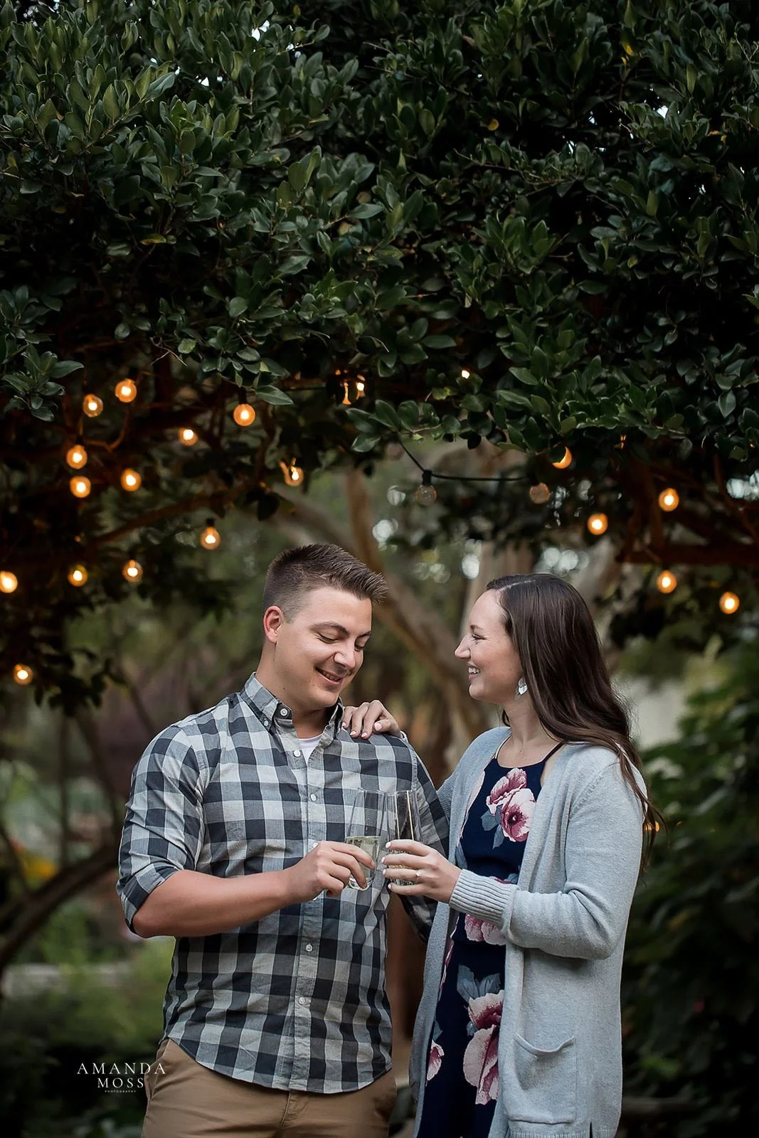 young couple toasts with champagne to celebrate being newly engaged rosies wine bar