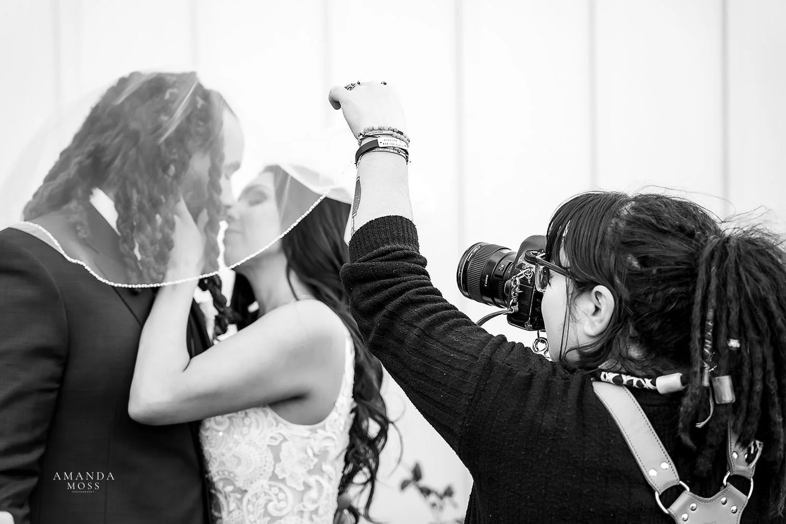 Black and white photo of wedding photographer amanda moss photography taking photo of bride and groom under the veil