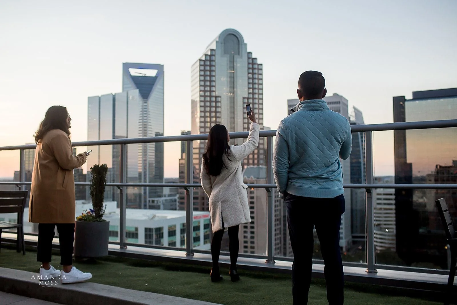 three people look over the charlotte skyline from the fahrenheit rooftop patio
