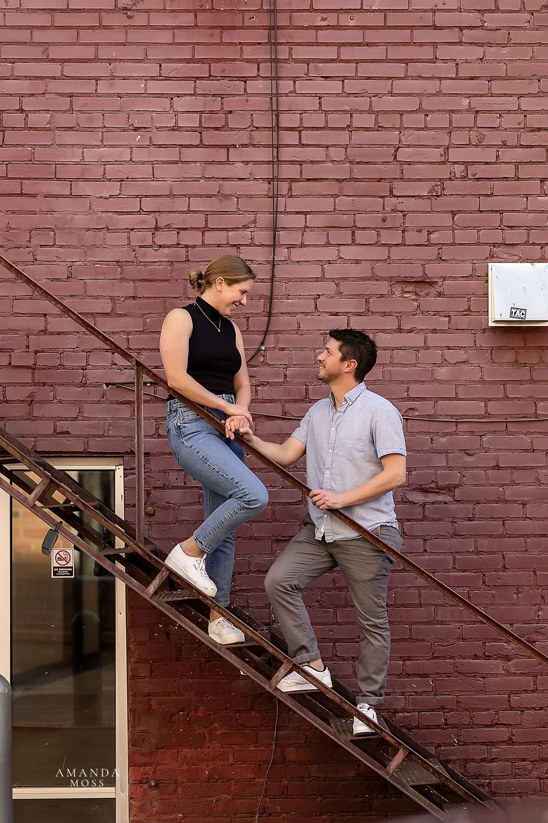 couple poses on stairs for engagement session in noda charlotte nc