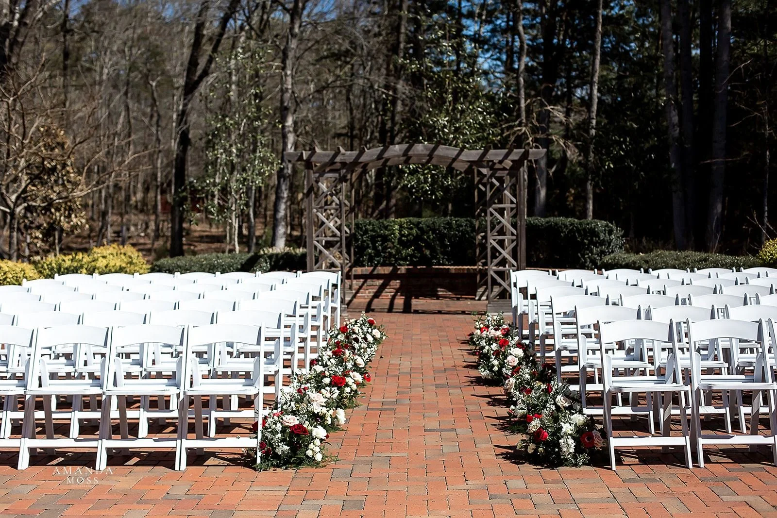 wedding ceremony set up with red, white and pink flowers at barn of chapel hill