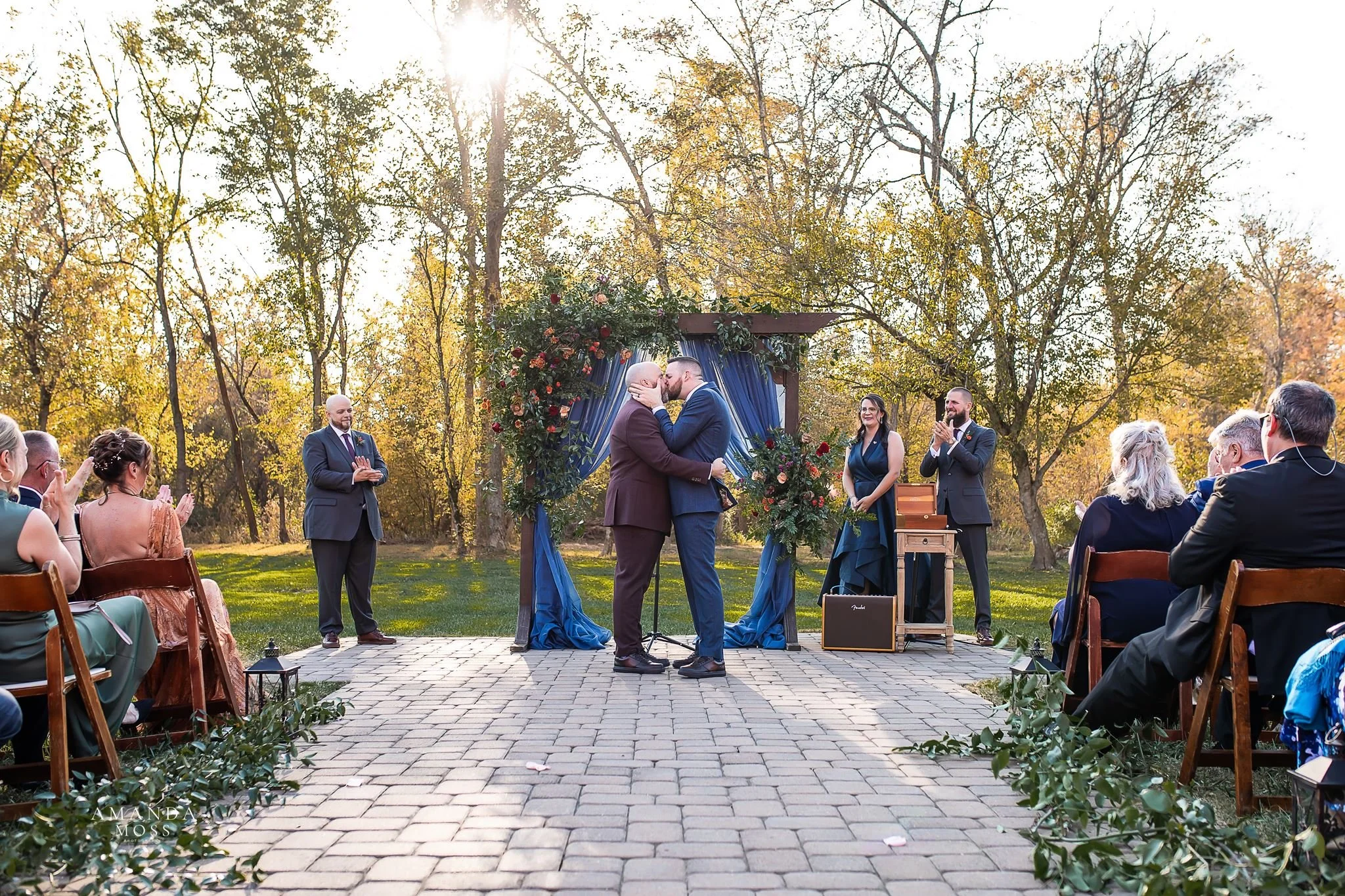 two grooms share first kiss as husbands at outdoor fall lgbt wedding ceremony at providence cotton mill in maiden nc