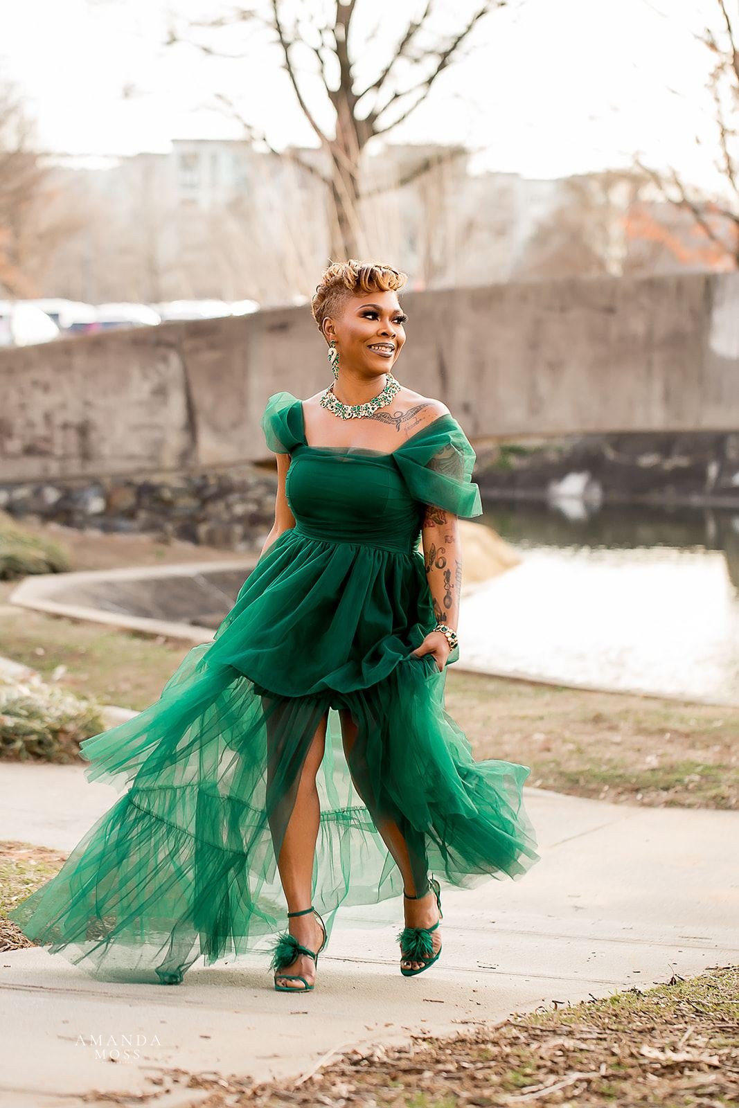 woman twirls in green chiffon dress at outdoor photo session at marshall park in charlotte nc