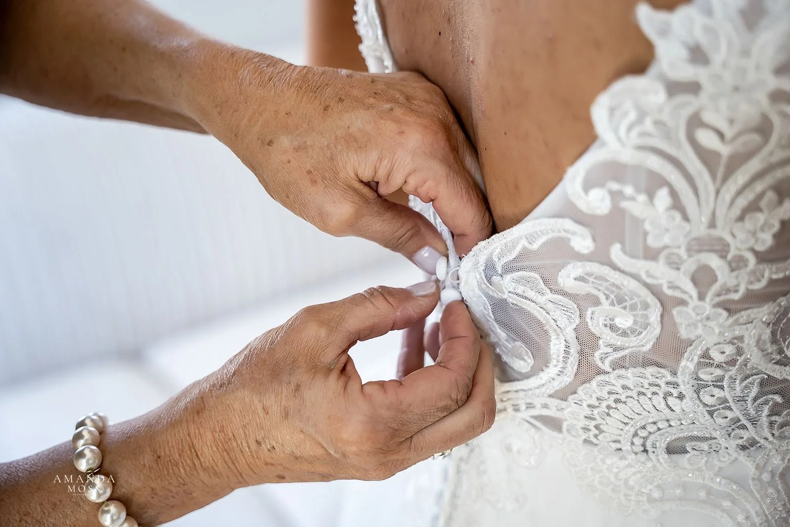 close up of hands buttoning a lace wedding dress