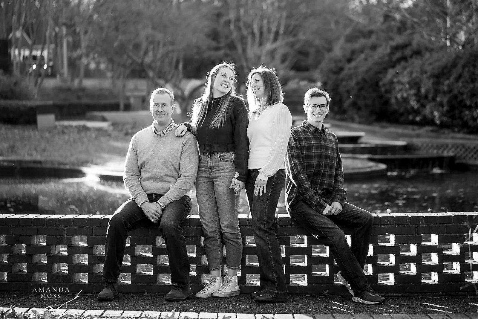 black and white family portrait of mom and dad with their son and daughter in front of a pond